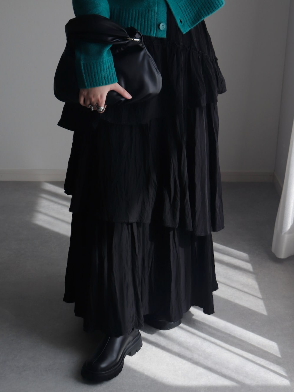 ブラック系のスカート、グリーン系のカーディガン/ボレロ、ブラック系のハンドバッグを着用したレディースの秋コーディネートの3枚目の写真