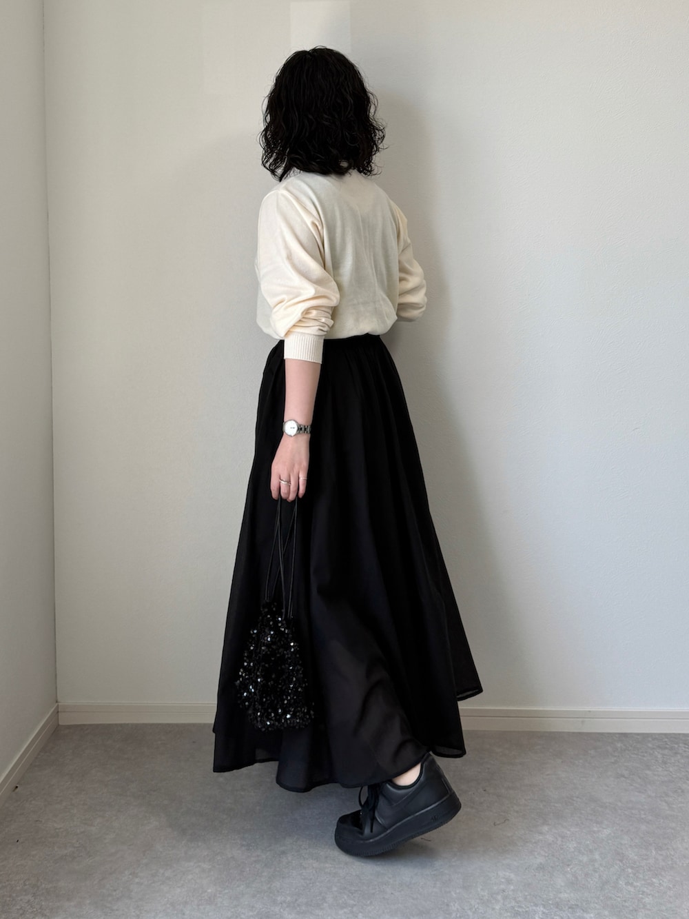 ブラック系のショルダーバッグ、ブラック系のスカート、ブラック系のスニーカーを着用したレディースの春コーディネートの2枚目の写真