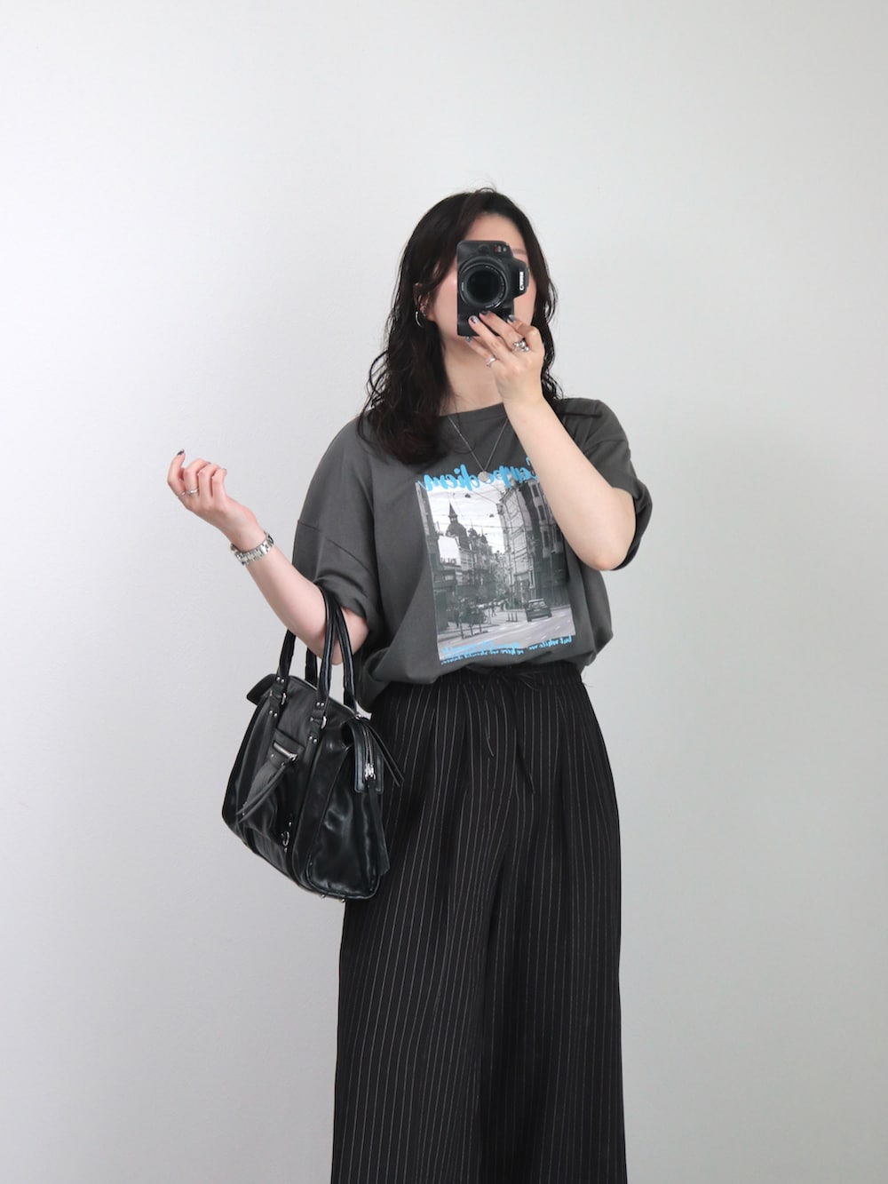 ブラック系のスラックス、グレー系のTシャツ/カットソー、ブラック系のサンダルを着用したレディースの春コーディネートの2枚目の写真