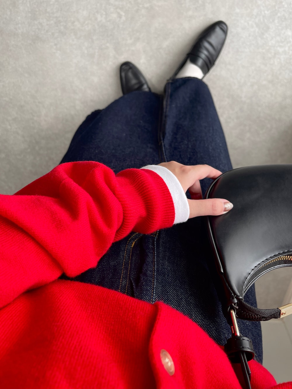 ブラック系のレインシューズ、ブルー系のデニムスカート、レッド系のカーディガン/ボレロを着用したレディースの秋コーディネートの4枚目の写真