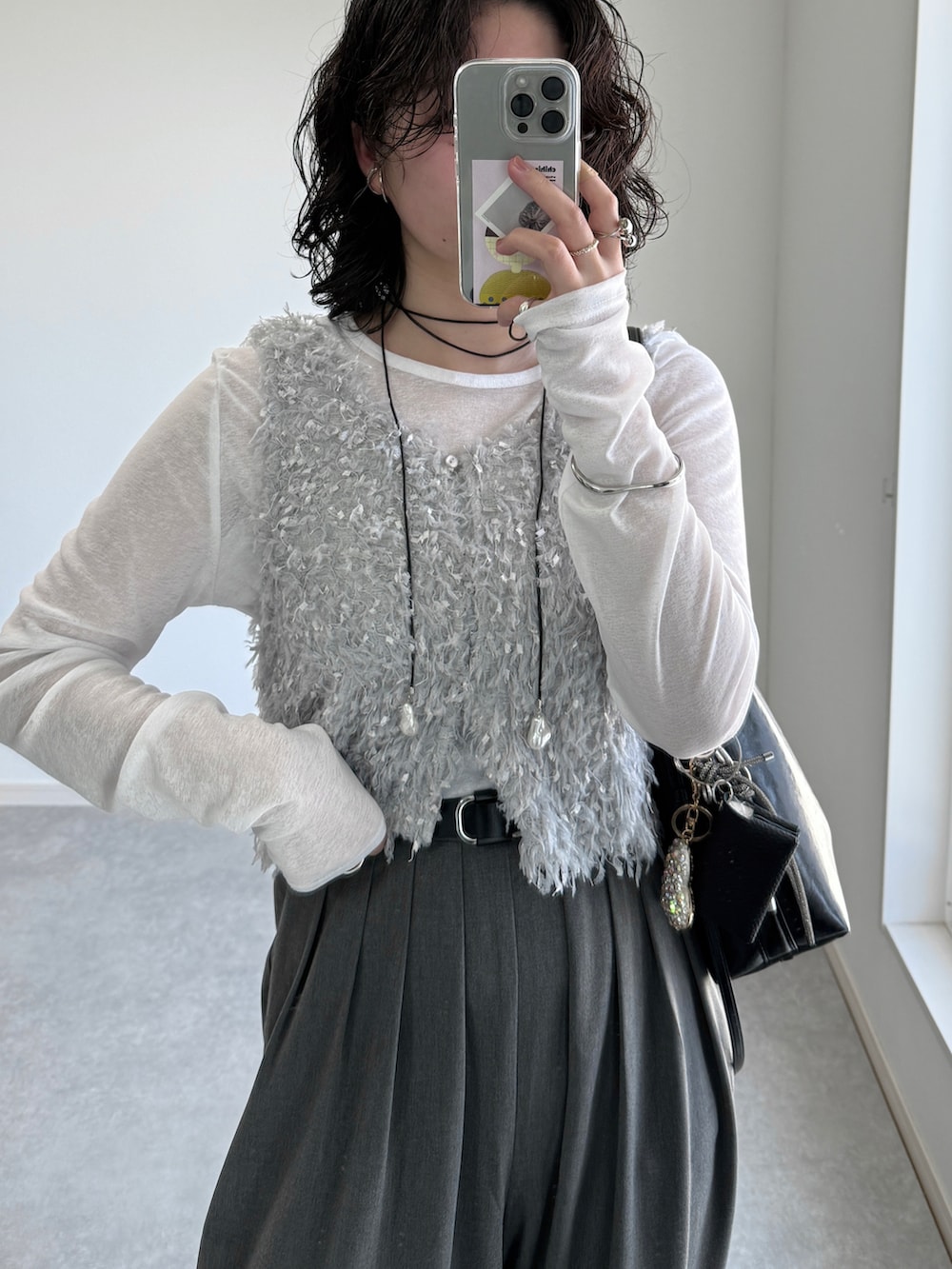 グレー系のスラックス、グレー系のベスト、ホワイト系のTシャツ/カットソーを着用したレディースの春コーディネートの2枚目の写真