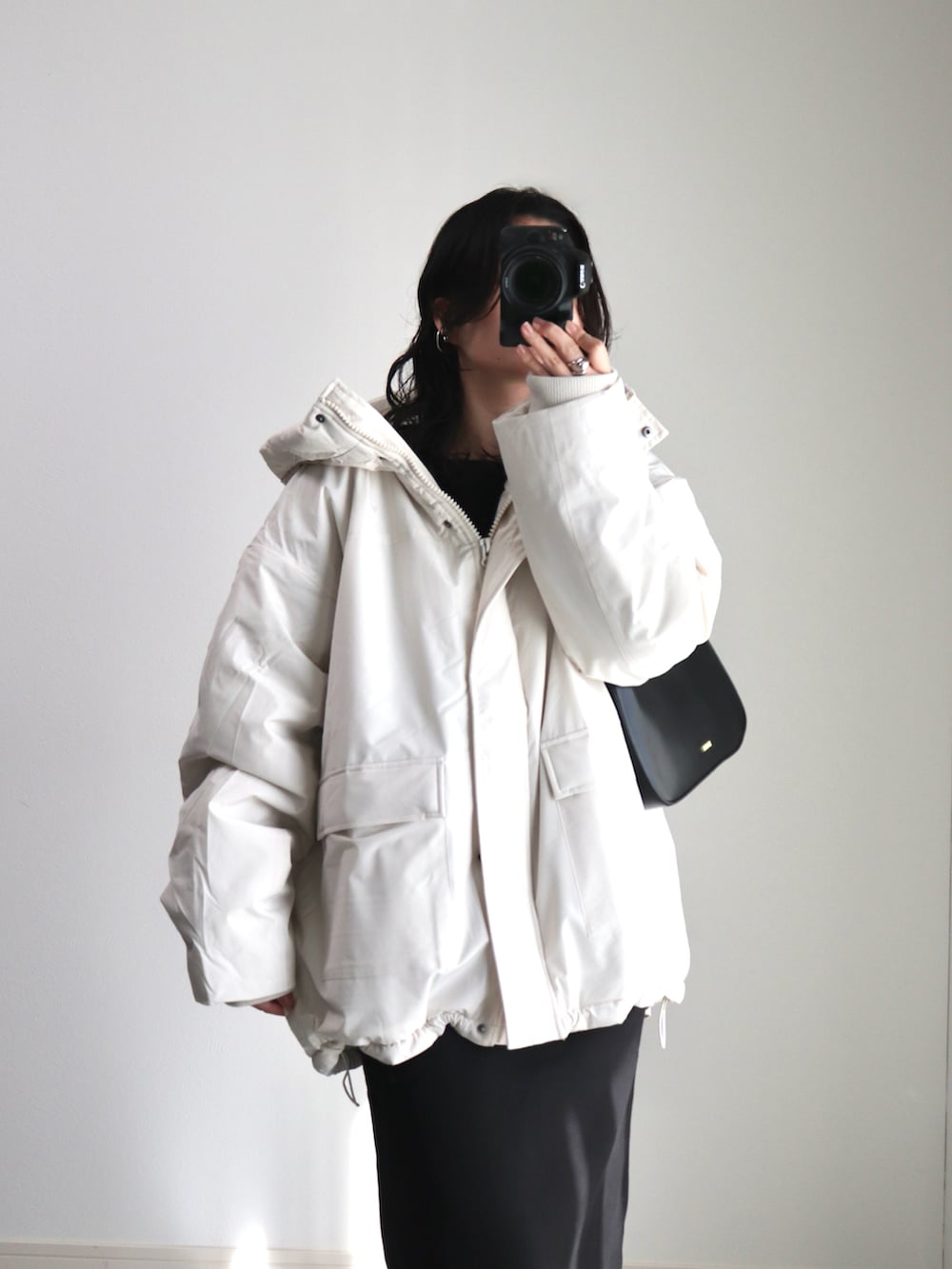 ブラック系のワンピース、ブラック系のハンドバッグ、ブラック系のスニーカーを着用したレディースの冬コーディネートの3枚目の写真