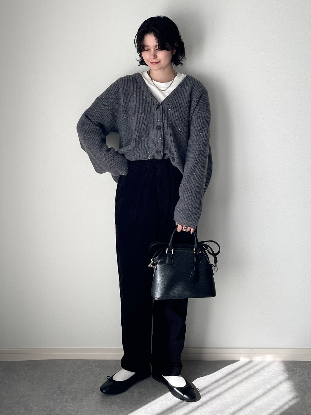グレー系のカーディガン/ボレロ、ホワイト系のTシャツ/カットソー、ブラック系のショルダーバッグを着用したレディースの秋コーディネートの2枚目の写真
