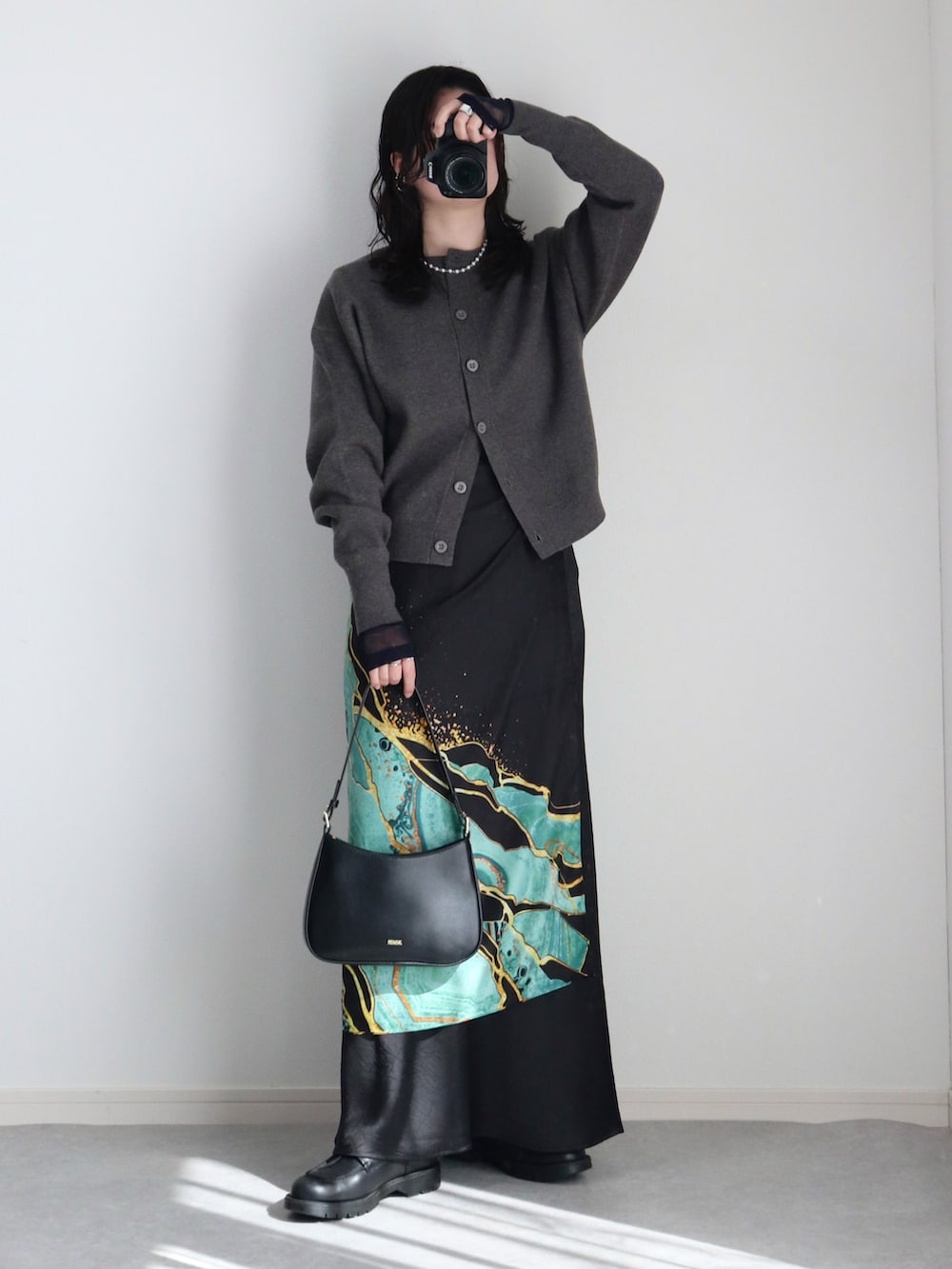 グレー系のカーディガン/ボレロ、ブラック系のスカート、ブラック系のハンドバッグを着用したレディースの冬コーディネートの2枚目の写真