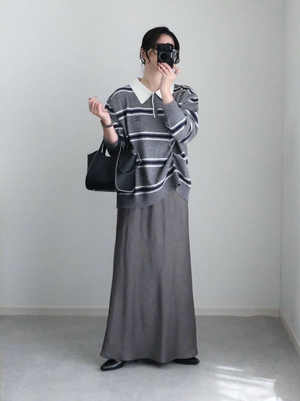 グレー系のニット/セーター、ブラック系のショルダーバッグ、グレー系のスカートを着用したレディースの秋コーディネートの4枚目の写真