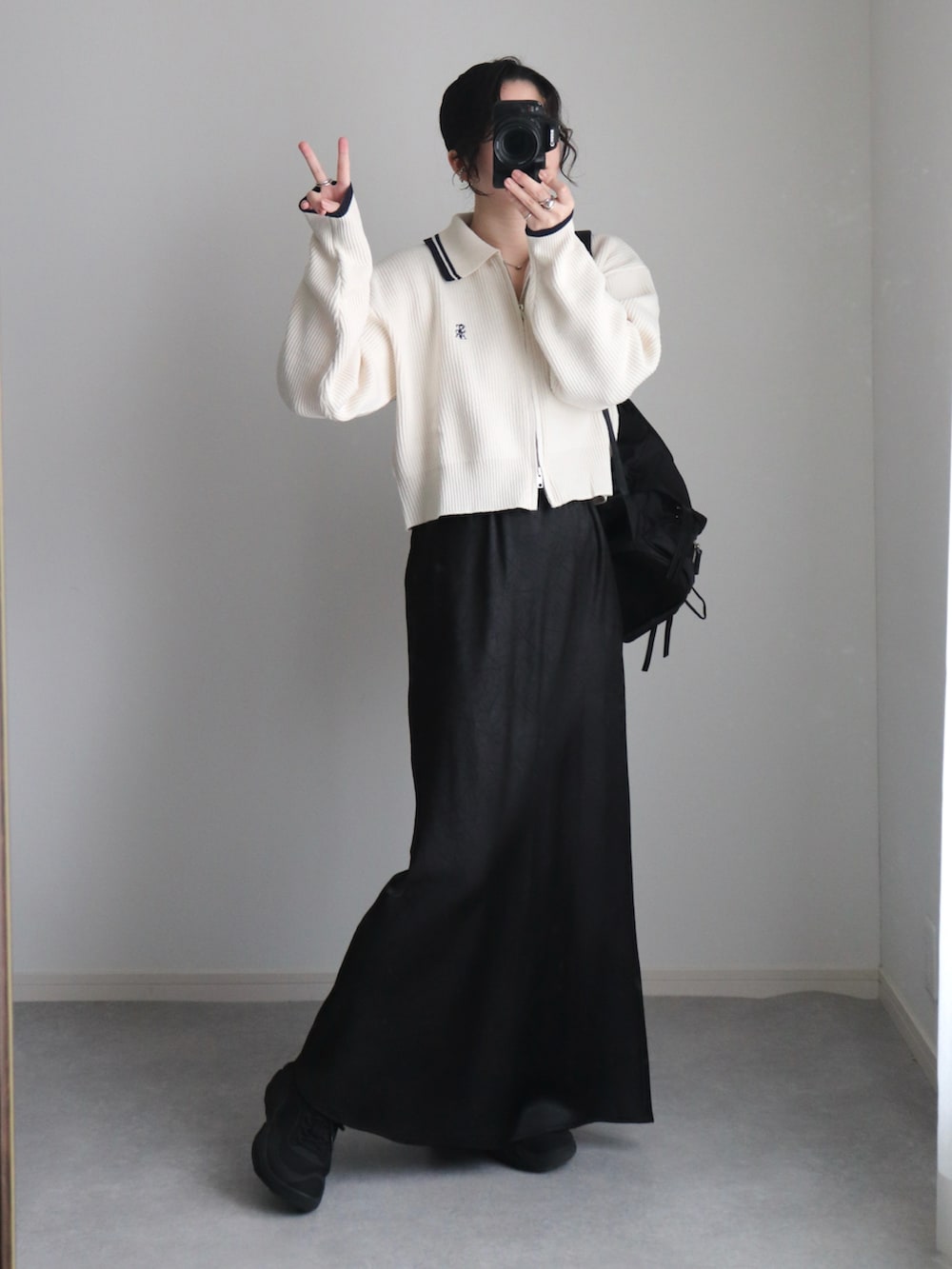 ホワイト系のニット/セーター、ブラック系のスカート、ブラック系のバックパック/リュックを着用したレディースの秋コーディネートの3枚目の写真