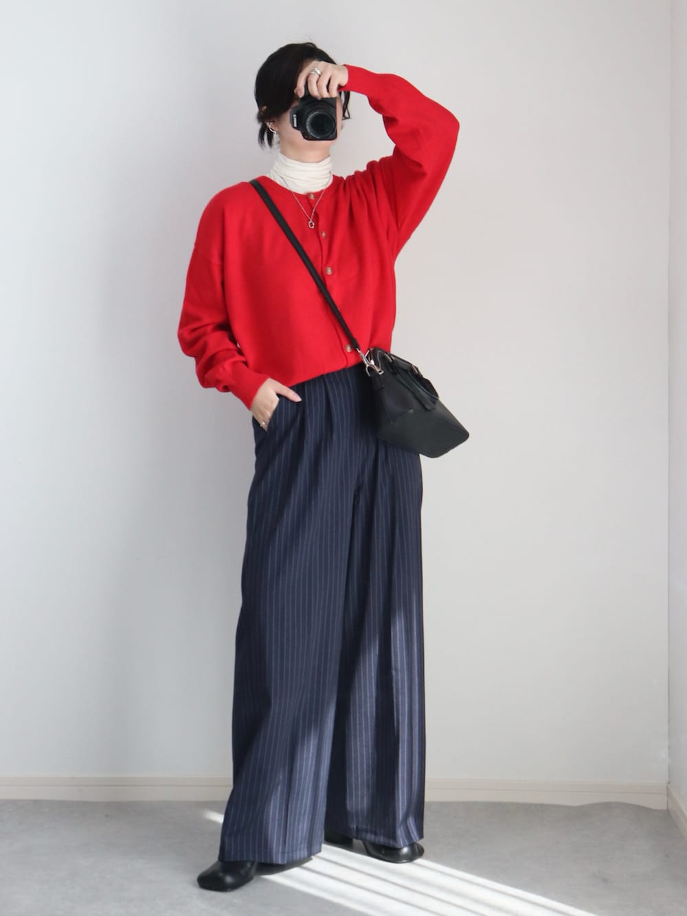 レッド系のカーディガン/ボレロ、ブラック系のブルゾン、ブルー系のスラックスを着用したレディースの秋コーディネートの2枚目の写真