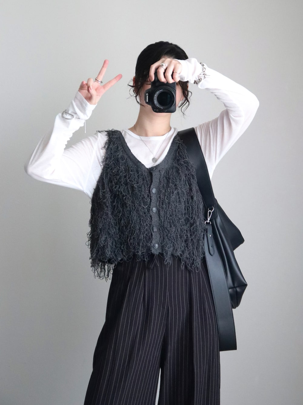 グレー系のベスト、ブラック系のスラックス、ブラック系のショルダーバッグを着用したレディースの秋コーディネートの3枚目の写真