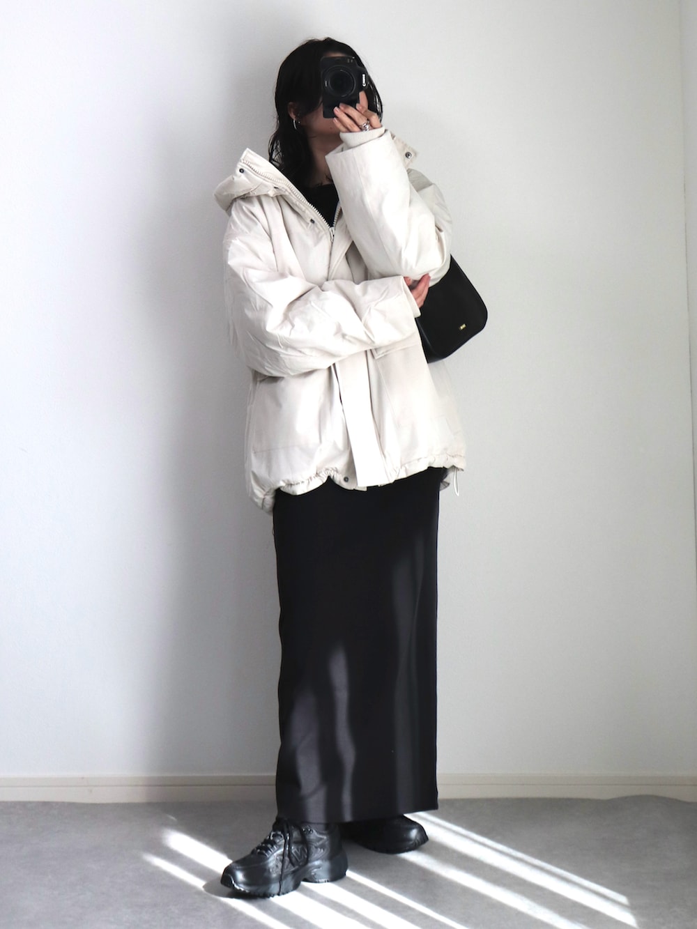 ブラック系のワンピース、ブラック系のハンドバッグ、ブラック系のスニーカーを着用したレディースの冬コーディネートの2枚目の写真