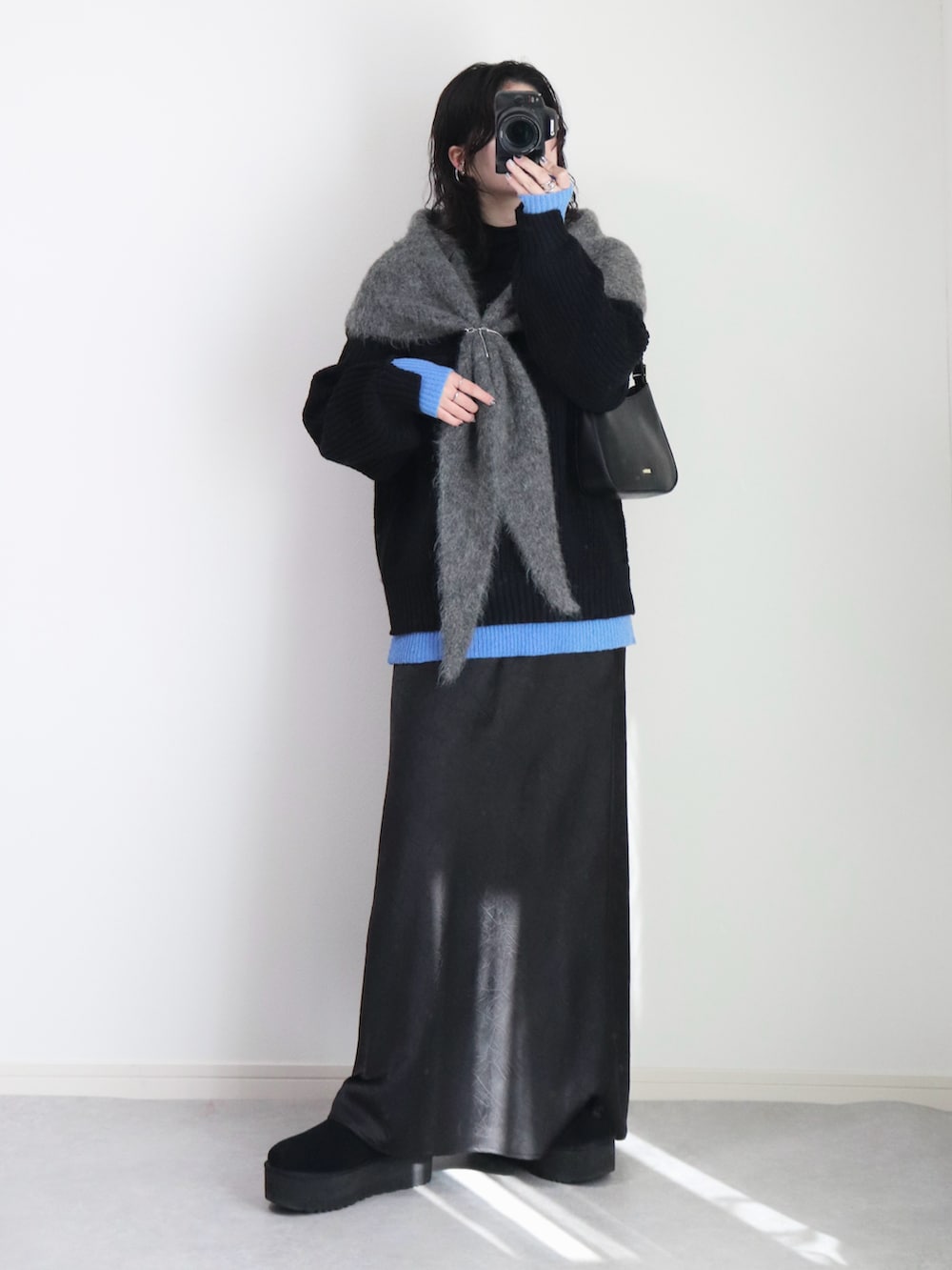 ブラック系のニット/セーター、ブラック系のスカート、ブラック系のハンドバッグを着用したレディースの冬コーディネートの3枚目の写真