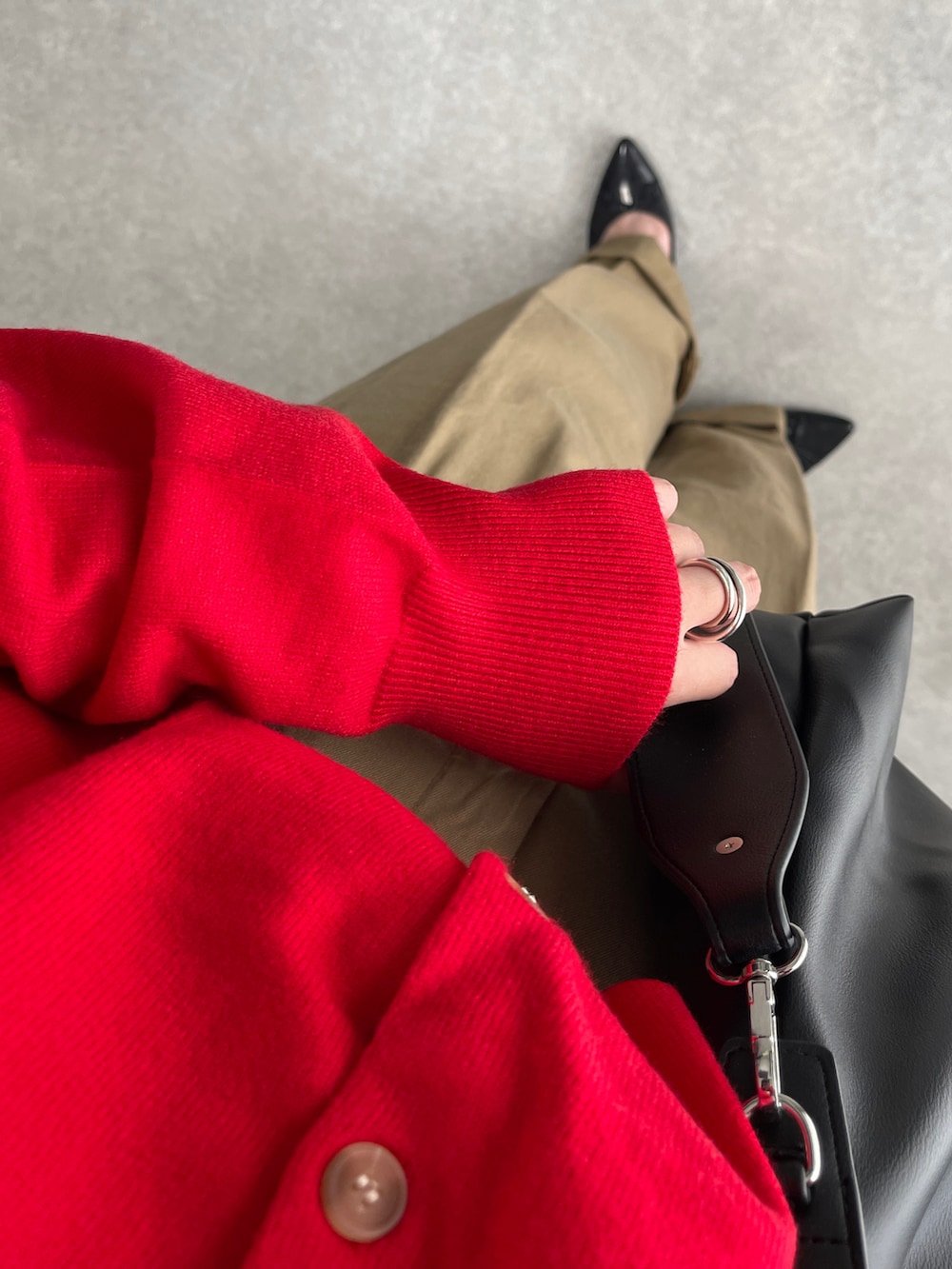 レッド系のカーディガン/ボレロ、ブラック系のショルダーバッグ、ベージュ系のチノパンツを着用したレディースの秋コーディネートの4枚目の写真