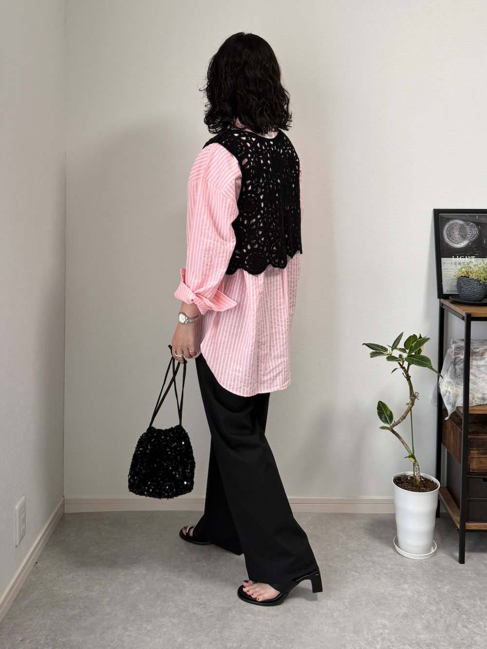 ブラック系のスラックス、ブラック系のサンダル、シルバー系のショルダーバッグを着用したレディースの夏コーディネートの2枚目の写真