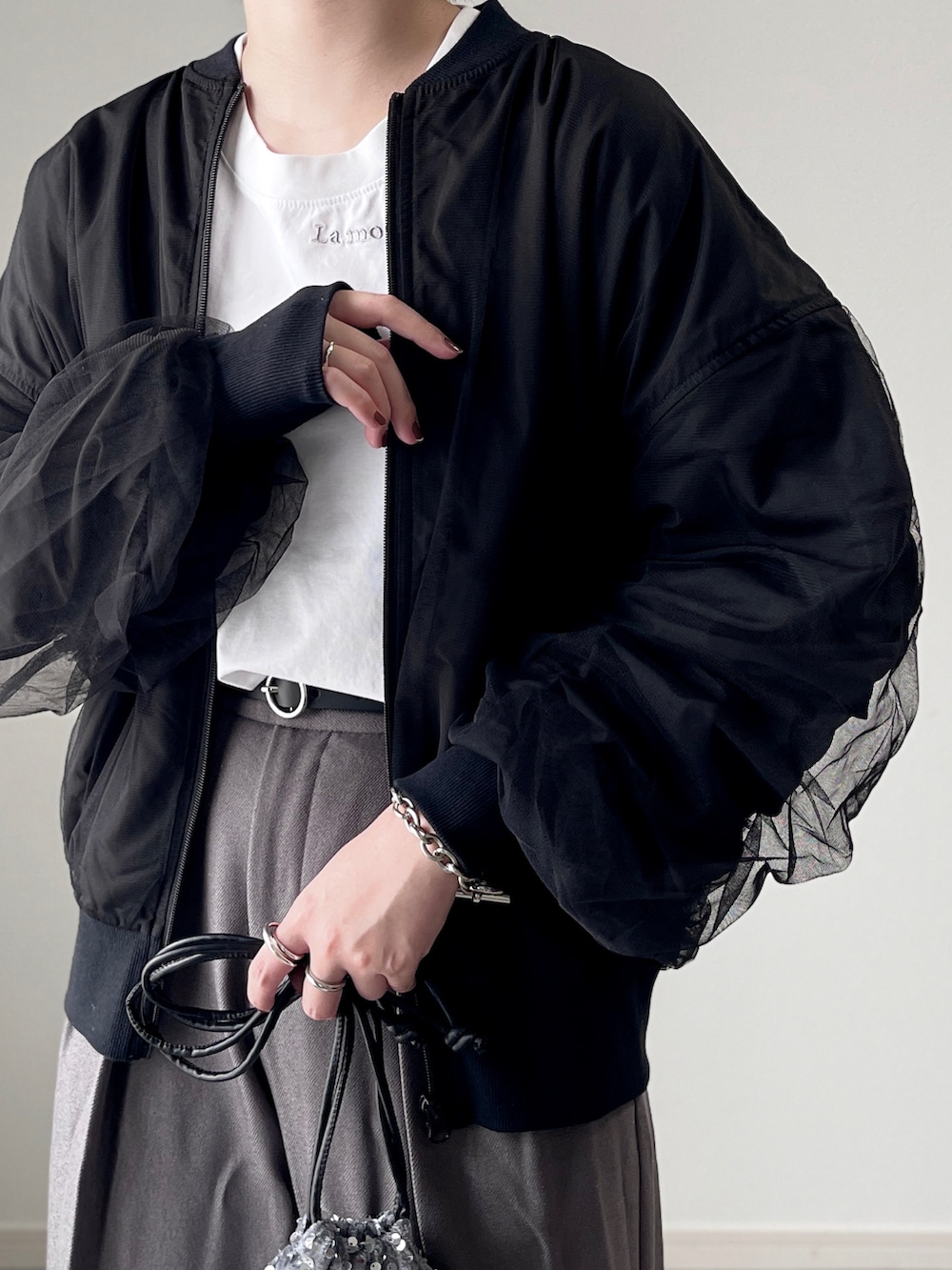 ブラック系のブーツ、グレー系のスラックス、シルバー系のショルダーバッグを着用したレディースの秋コーディネートの3枚目の写真