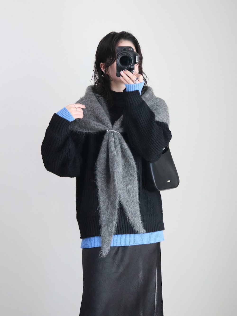 ブラック系のニット/セーター、ブラック系のスカート、ブラック系のハンドバッグを着用したレディースの冬コーディネートの4枚目の写真