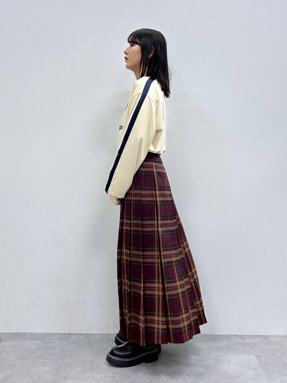 ブラック系のローファー、レッド系のスカート、ホワイト系のTシャツ/カットソーを着用したレディースの秋コーディネートの3枚目の写真