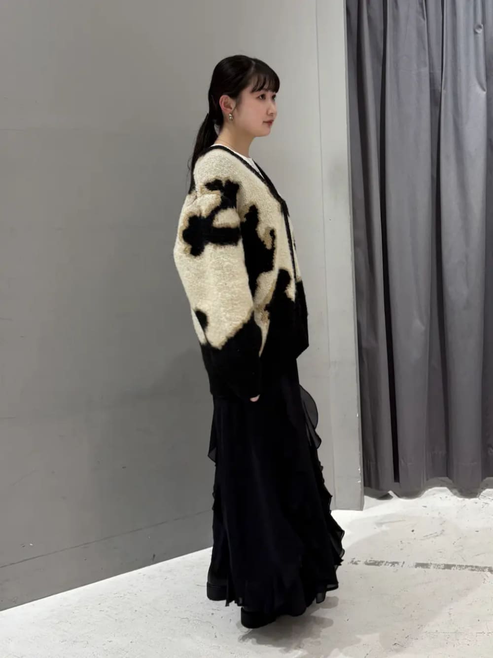 ベージュ系のカーディガン/ボレロ、ホワイト系のTシャツ/カットソー、ブラック系のスカートを着用したレディースの秋コーディネートの2枚目の写真