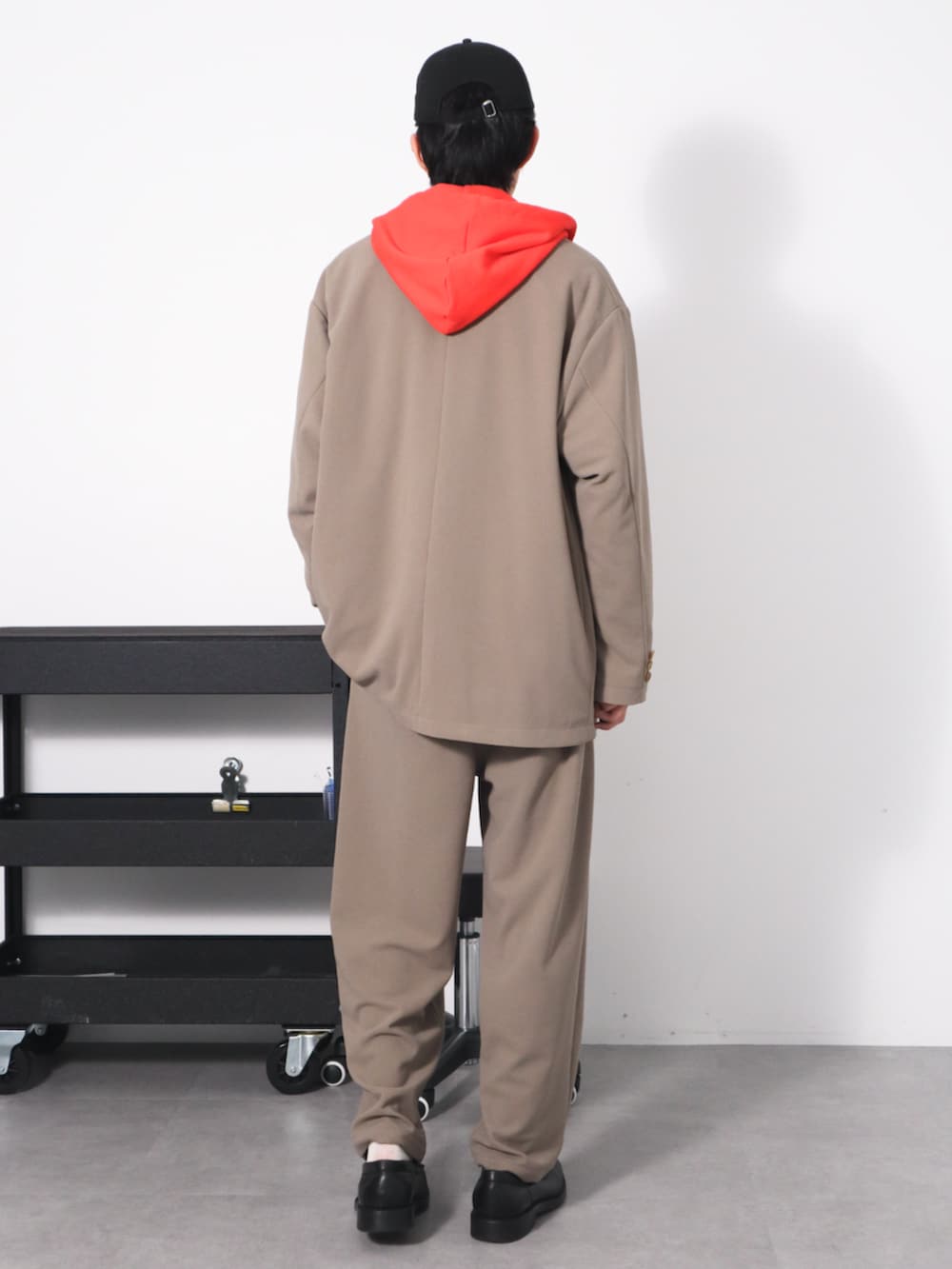 レッド系のパーカー、ベージュ系のセットアップを着用したメンズの春コーディネートの2枚目の写真