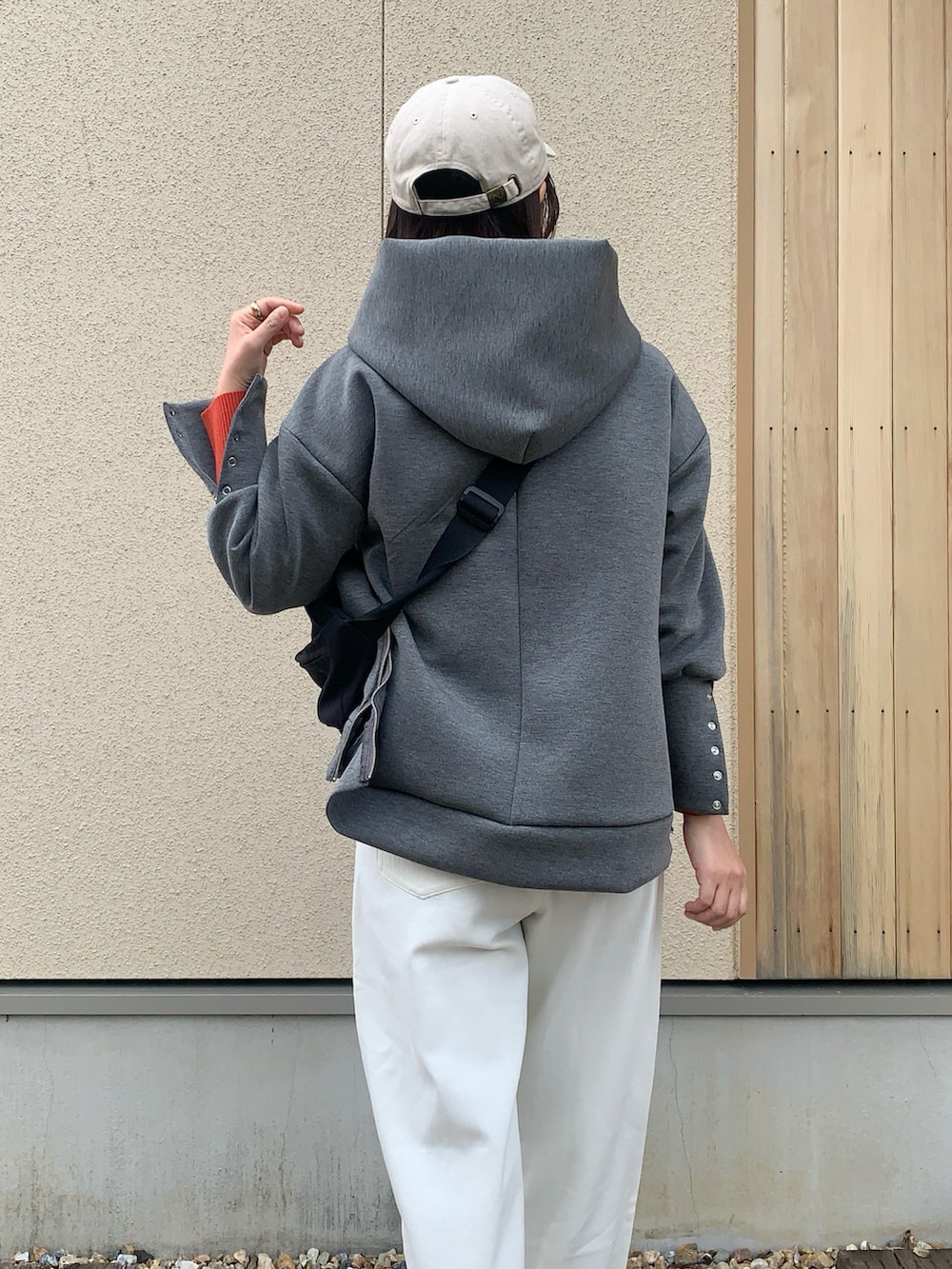 グレー系のパーカー、ホワイト系のデニムパンツ、ブラック系のボディバッグ/ウエストポーチを着用したレディースの春コーディネートの4枚目の写真