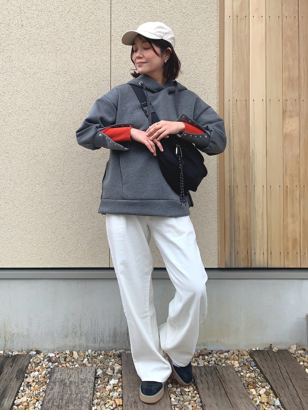 グレー系のパーカー、ホワイト系のデニムパンツ、ブラック系のボディバッグ/ウエストポーチを着用したレディースの春コーディネートの3枚目の写真