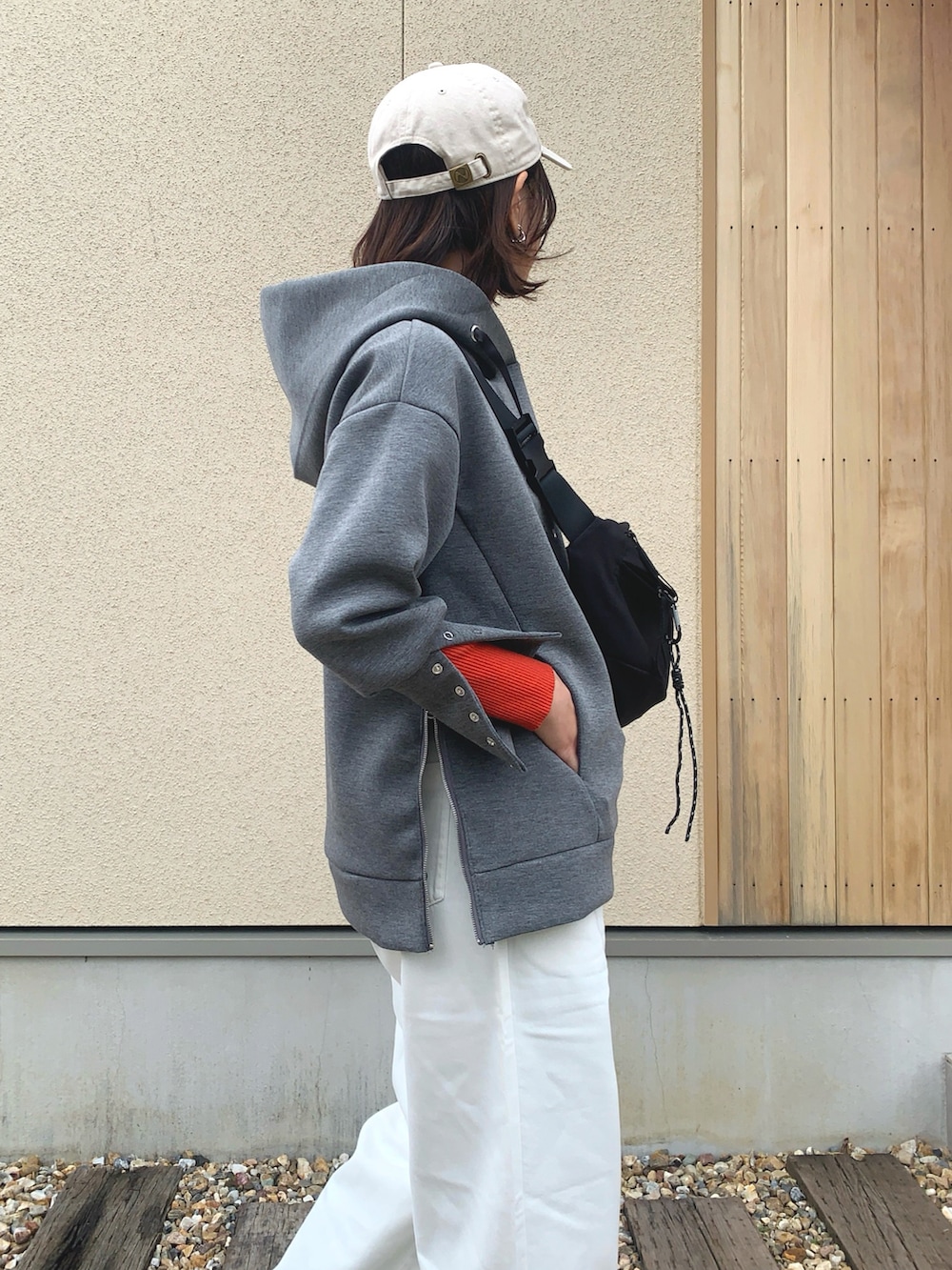 グレー系のパーカー、ホワイト系のデニムパンツ、ブラック系のボディバッグ/ウエストポーチを着用したレディースの春コーディネートの2枚目の写真