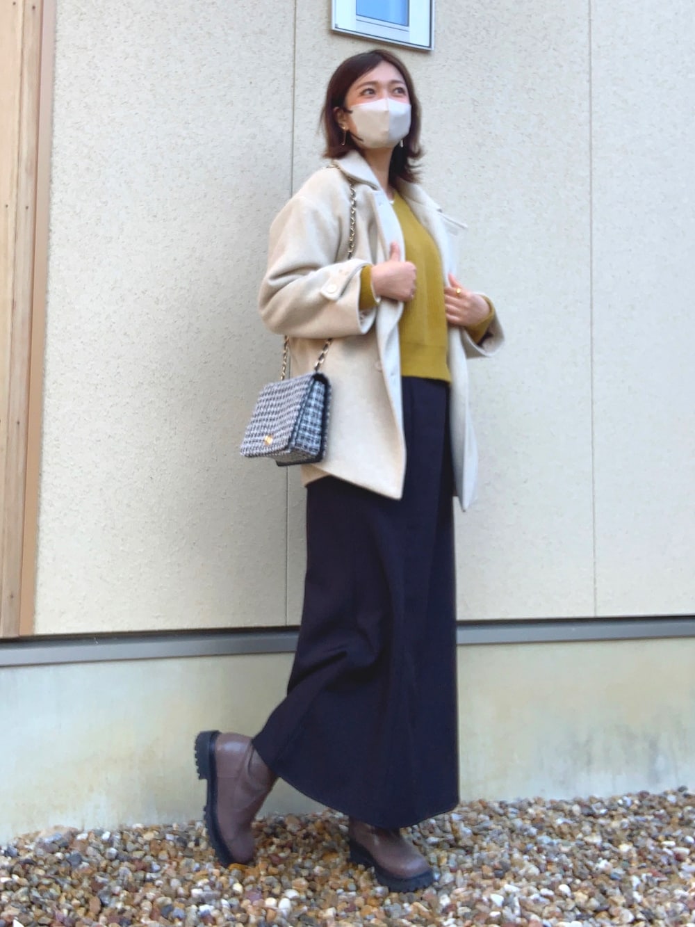 ホワイト系のジャケット/アウター、イエロー系のニット/セーター、ブラック系のスカートを着用したレディースの冬コーディネートの3枚目の写真