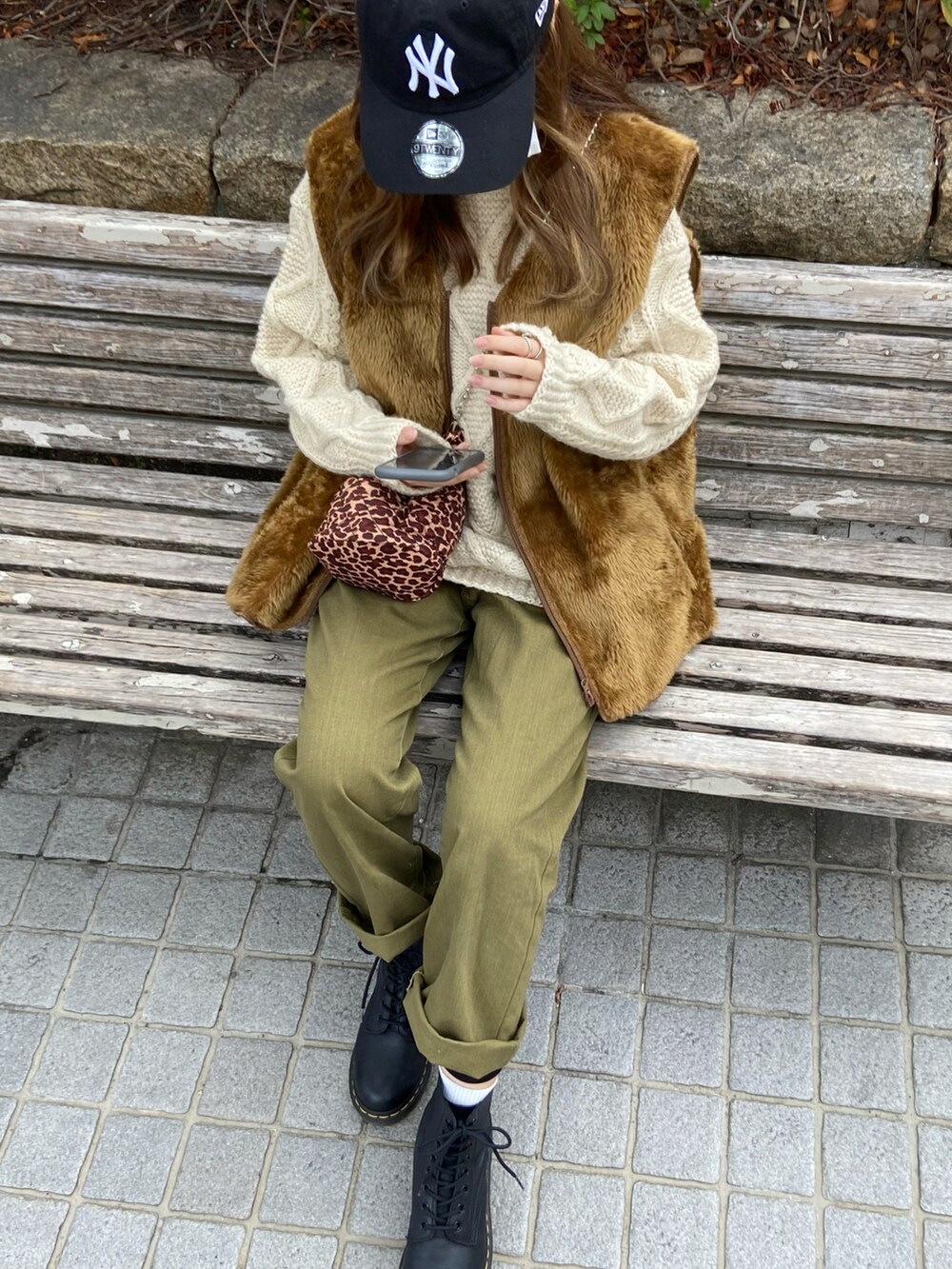 ブラウン系のショルダーバッグ、ブラック系のブーツ、ブラック系のキャップを着用したレディースの春コーディネートの2枚目の写真