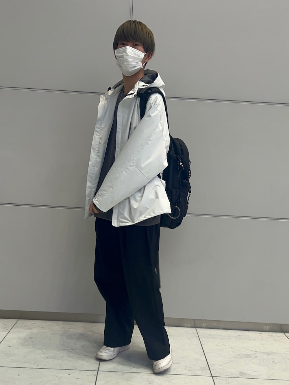 グレー系のトップス、ホワイト系のスニーカー、ブラック系のバックパック/リュックを着用したメンズの春コーディネートの2枚目の写真