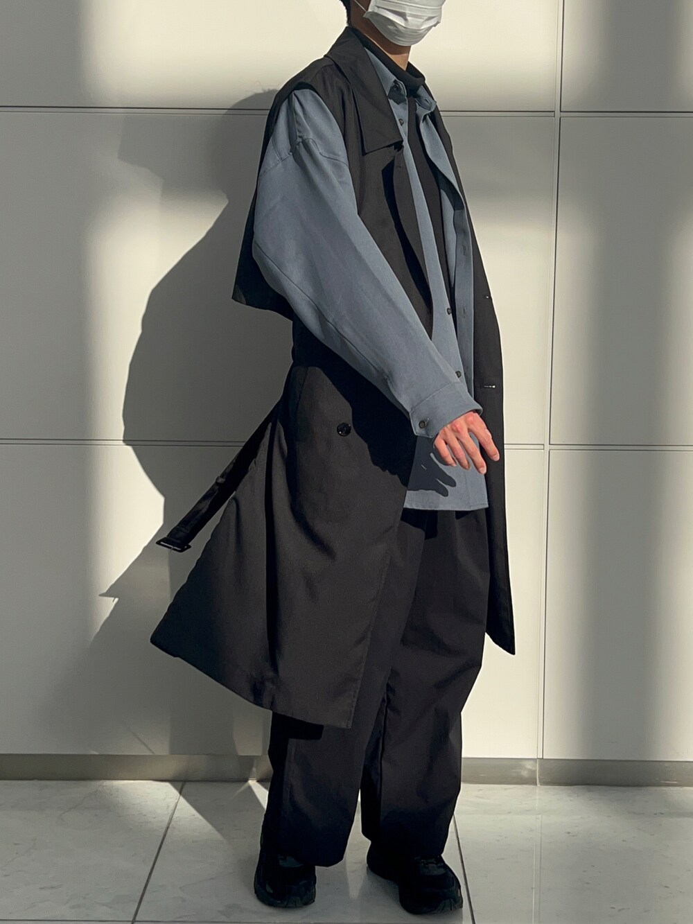 ブルー系のシャツ/ブラウス、ブラック系のトレンチコート、ブラック系のその他パンツを着用したメンズの春コーディネートの2枚目の写真