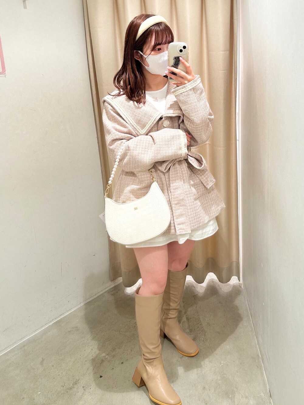 ホワイト系のショルダーバッグ、ベージュ系のブーツ、ホワイト系のスカートを着用したレディースの冬コーディネートの2枚目の写真