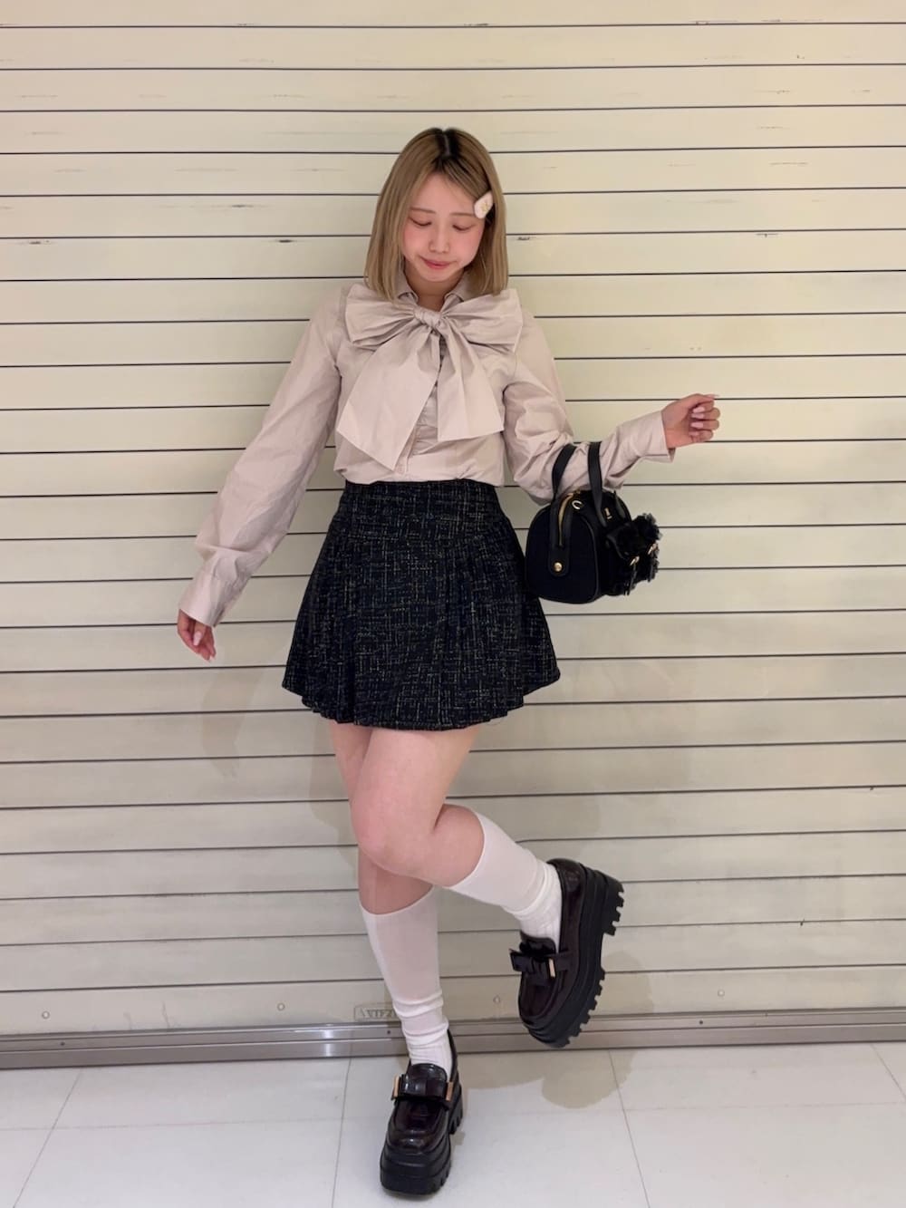 ピンク系のシャツ/ブラウス、ブラック系のスカート、ブラック系のショルダーバッグを着用したレディースの春コーディネートの2枚目の写真