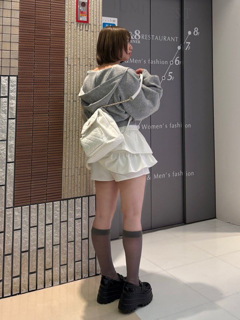 グレー系のパーカー、ホワイト系のスカート、ホワイト系のバックパック/リュックを着用したレディースの春コーディネートの2枚目の写真