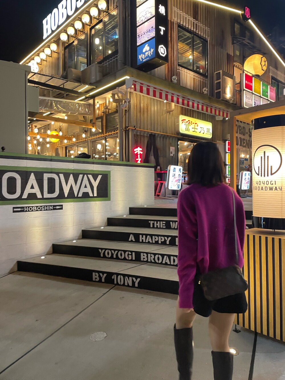 ブラック系のパンツ、ブラウン系のショルダーバッグ、ブラウン系のブーツを着用したレディースの春コーディネートの2枚目の写真