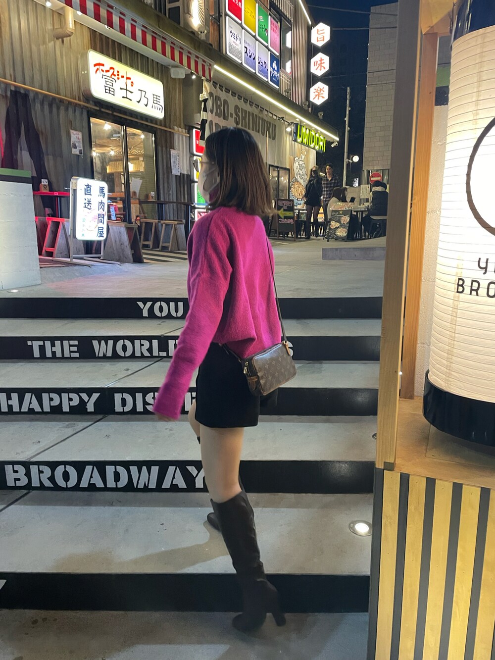 ブラック系のパンツ、ブラウン系のショルダーバッグ、ブラウン系のブーツを着用したレディースの春コーディネートの3枚目の写真