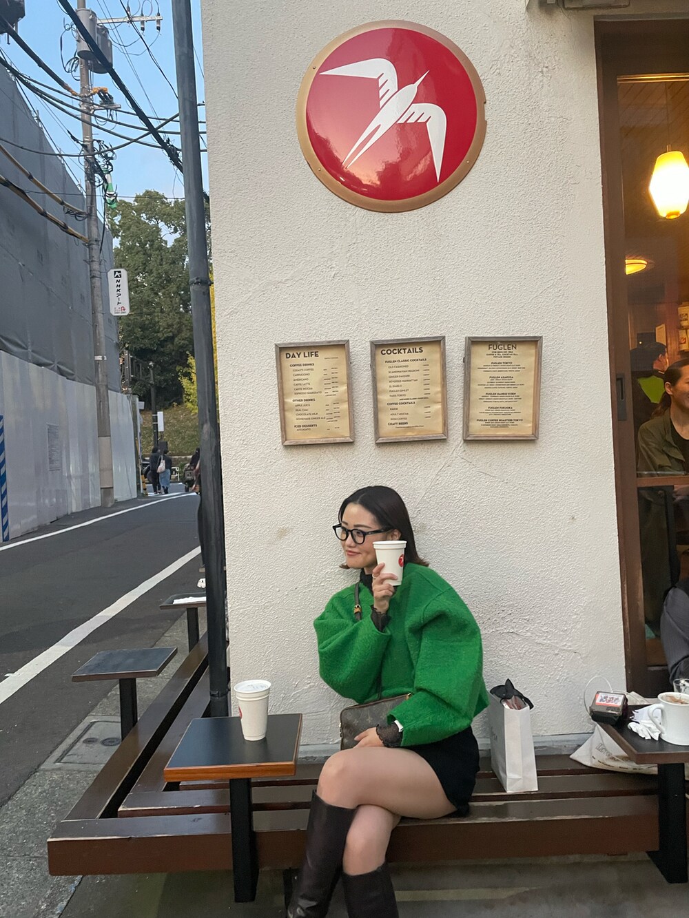 グリーン系のニット/セーター、ブラック系のパンツ、ブラウン系のブーツを着用したレディースの春コーディネートの2枚目の写真