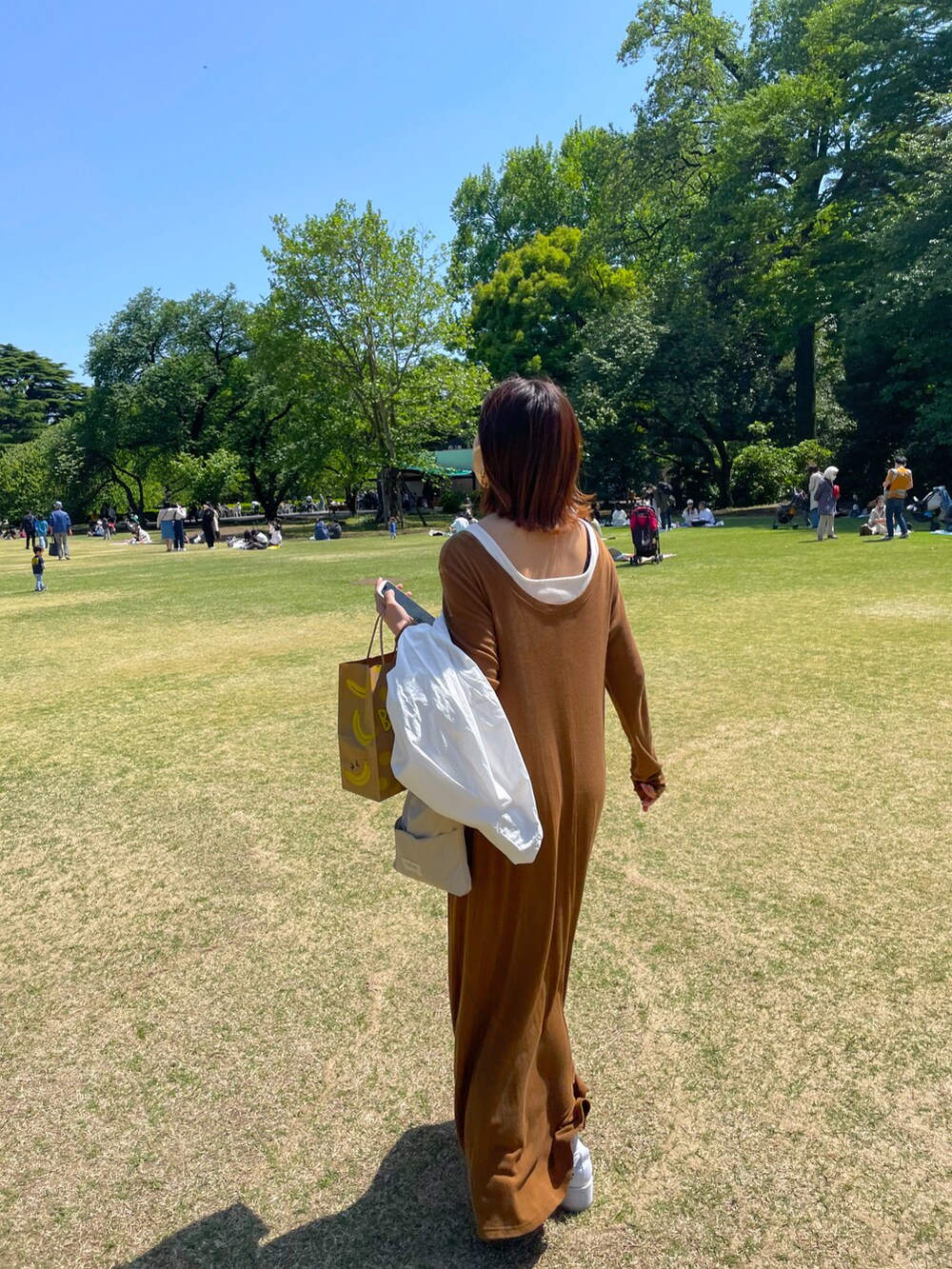 ホワイト系のショルダーバッグ、ブラウン系のスカートを着用したレディースの春コーディネートの2枚目の写真