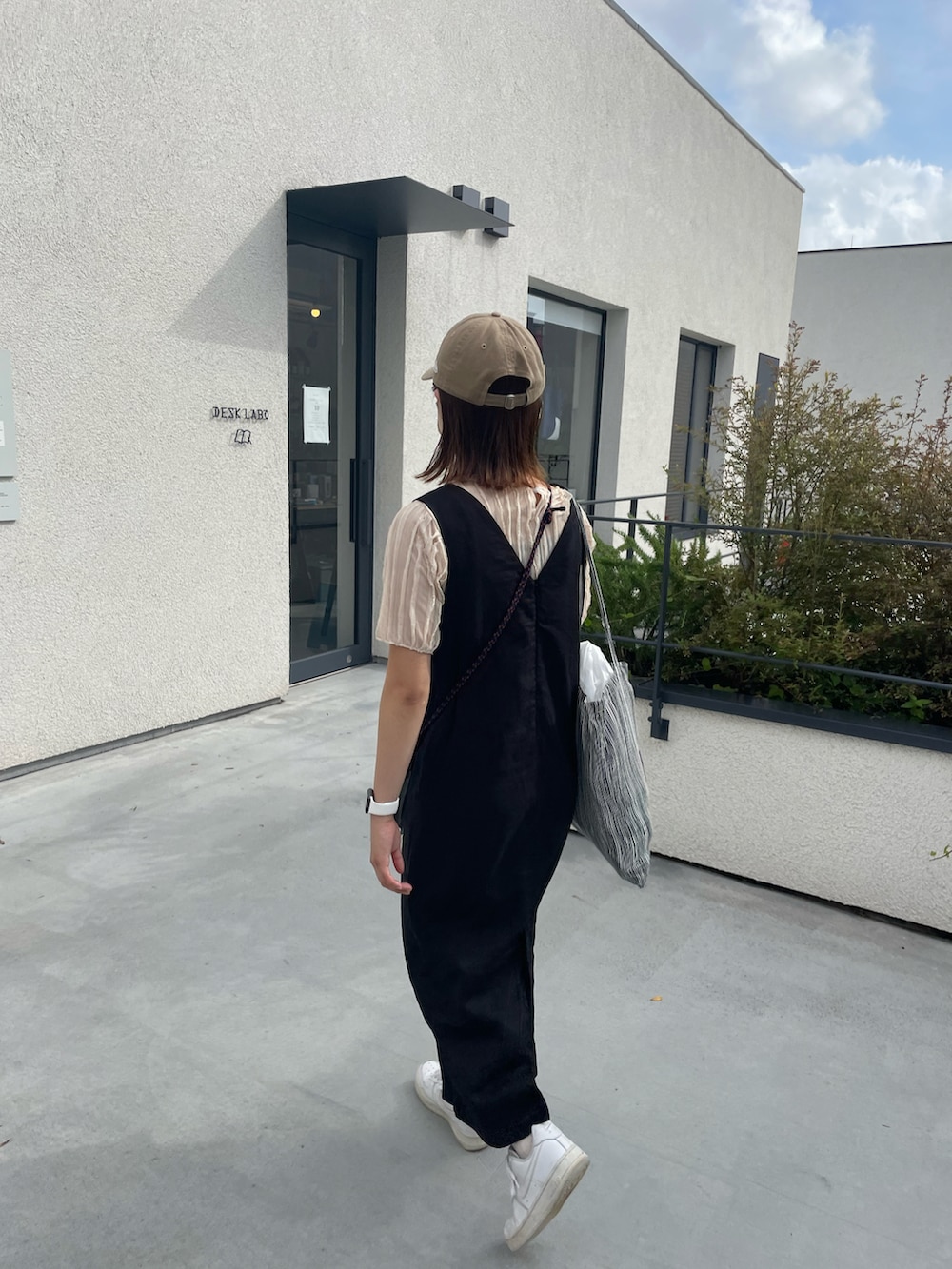 ブラック系のトートバッグ、ベージュ系のキャップを着用したレディースの春コーディネートの3枚目の写真