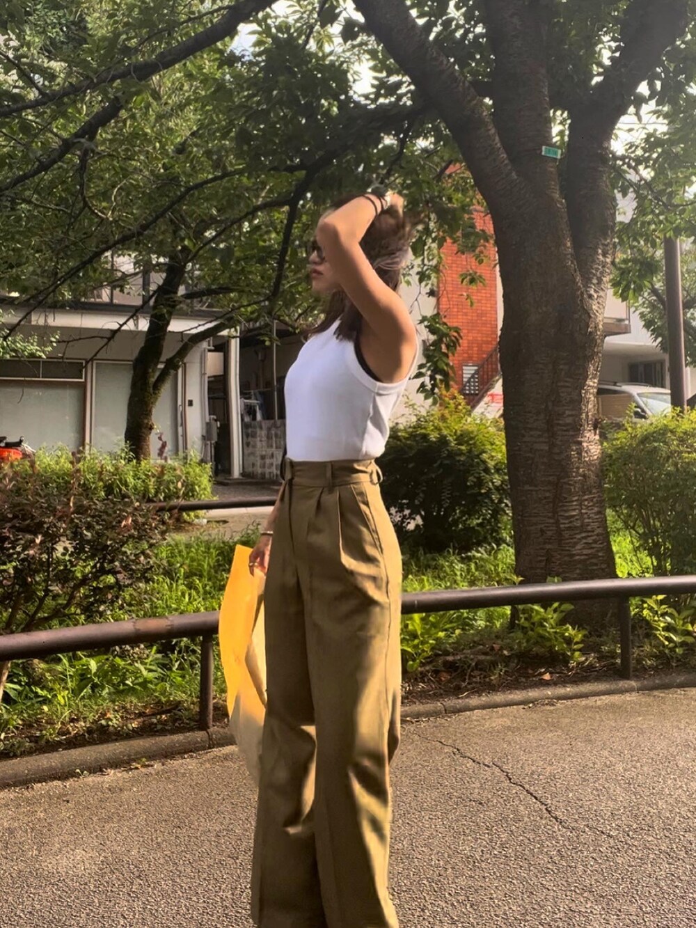 グリーン系のスラックス、ホワイト系のタンクトップを着用したレディースの春コーディネートの2枚目の写真