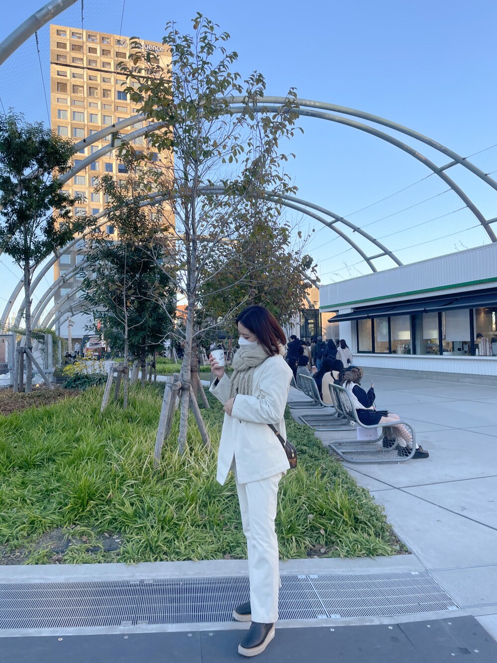 ブラウン系のショルダーバッグ、ベージュ系のマフラーを着用したレディースの春コーディネートの2枚目の写真