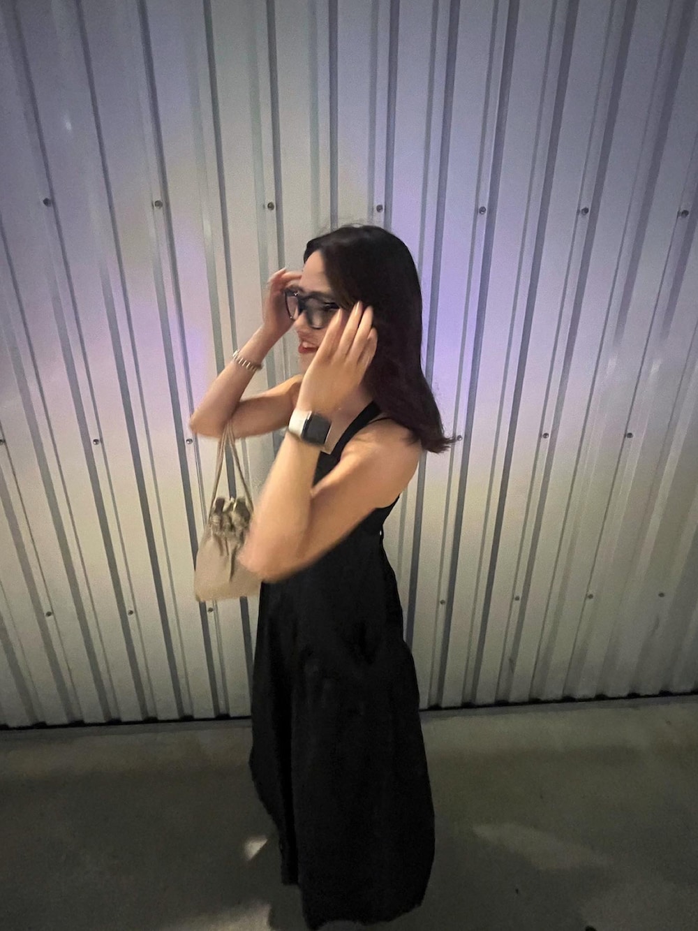 ベージュ系のショルダーバッグ、ブラック系のワンピース、ブラック系のメガネを着用したレディースの春コーディネートの2枚目の写真