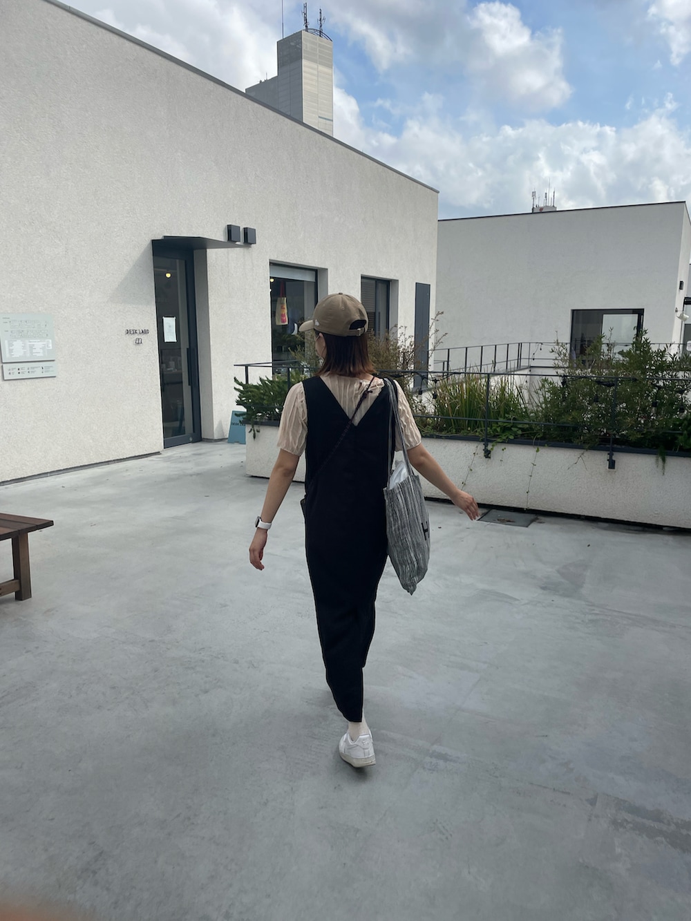 ブラック系のトートバッグ、ベージュ系のキャップを着用したレディースの春コーディネートの2枚目の写真