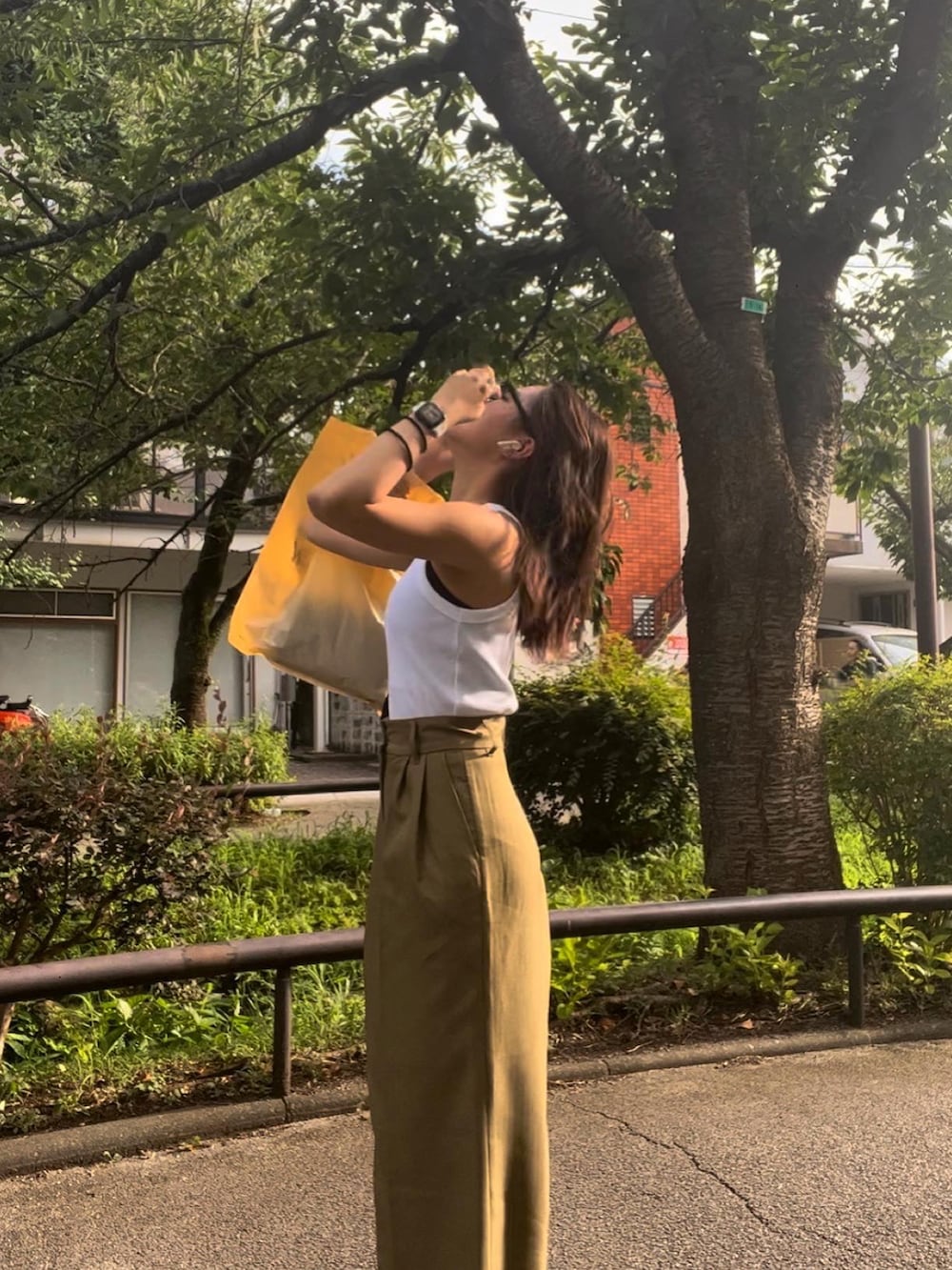 グリーン系のスラックス、ホワイト系のタンクトップを着用したレディースの春コーディネートの3枚目の写真