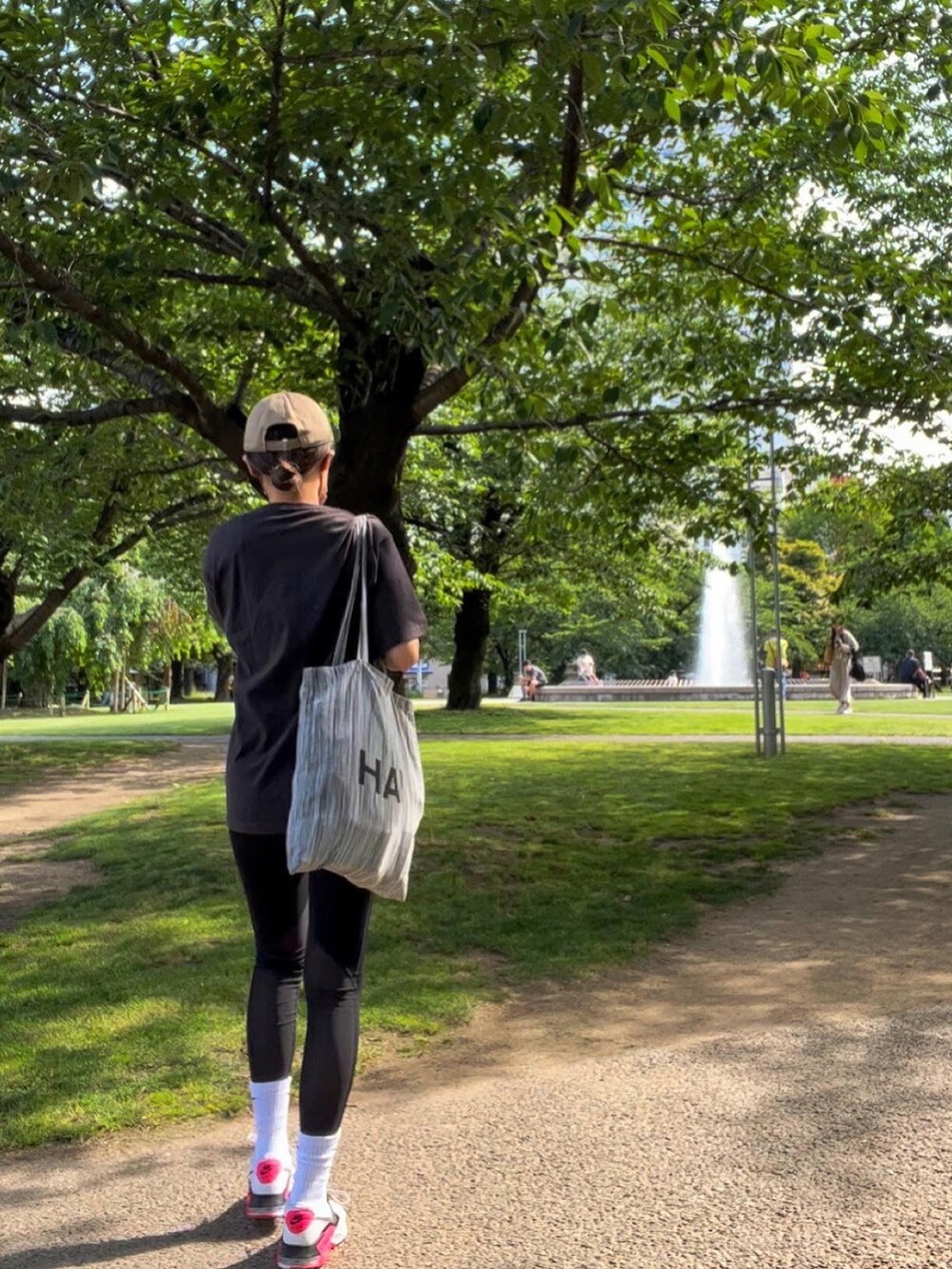 グレー系のTシャツ/カットソー、ホワイト系のスニーカー、ブラック系のスポーツグッズを着用したレディースの春コーディネートの2枚目の写真