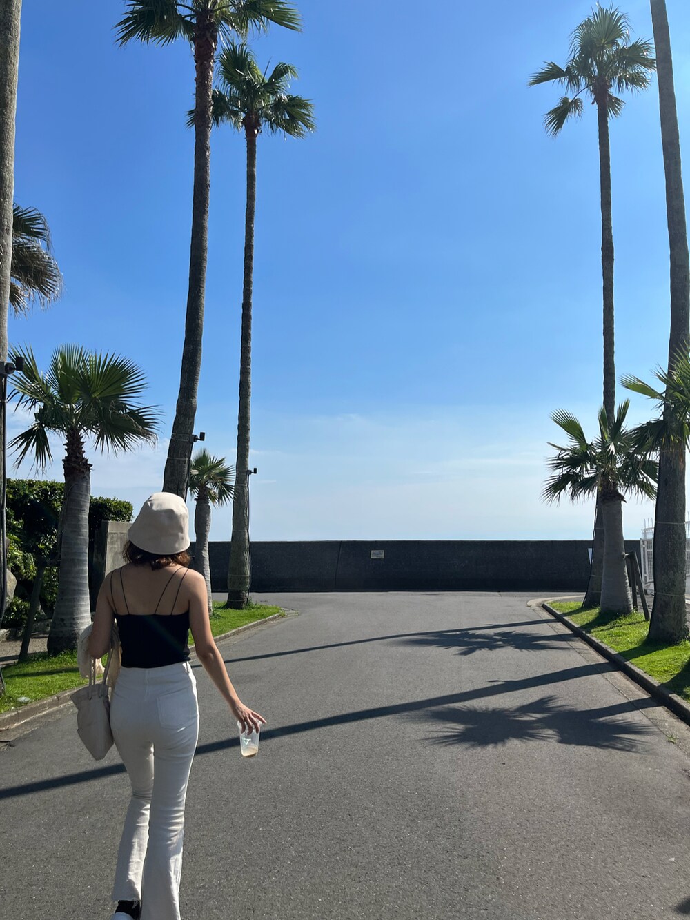 ホワイト系のデニムパンツ、ホワイト系のトートバッグ、ベージュ系のハットを着用したレディースの春コーディネートの2枚目の写真