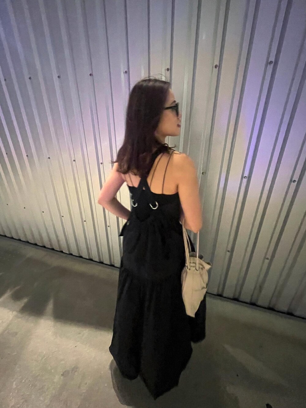 ベージュ系のショルダーバッグ、ブラック系のワンピース、ブラック系のメガネを着用したレディースの春コーディネートの4枚目の写真