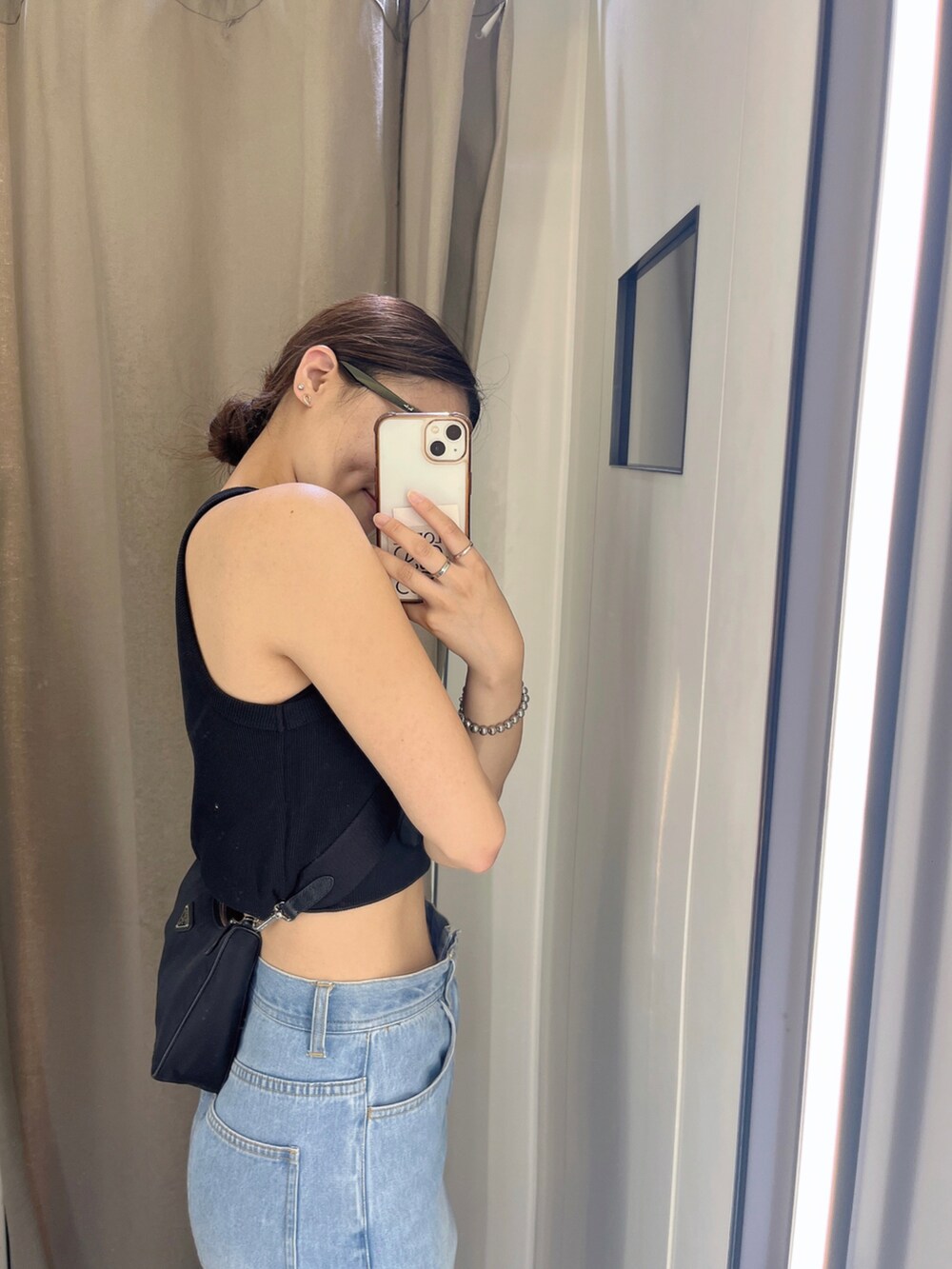 ブラック系のタンクトップ、ブルー系のデニムパンツ、ブラック系のバッグを着用したレディースの春コーディネートの2枚目の写真