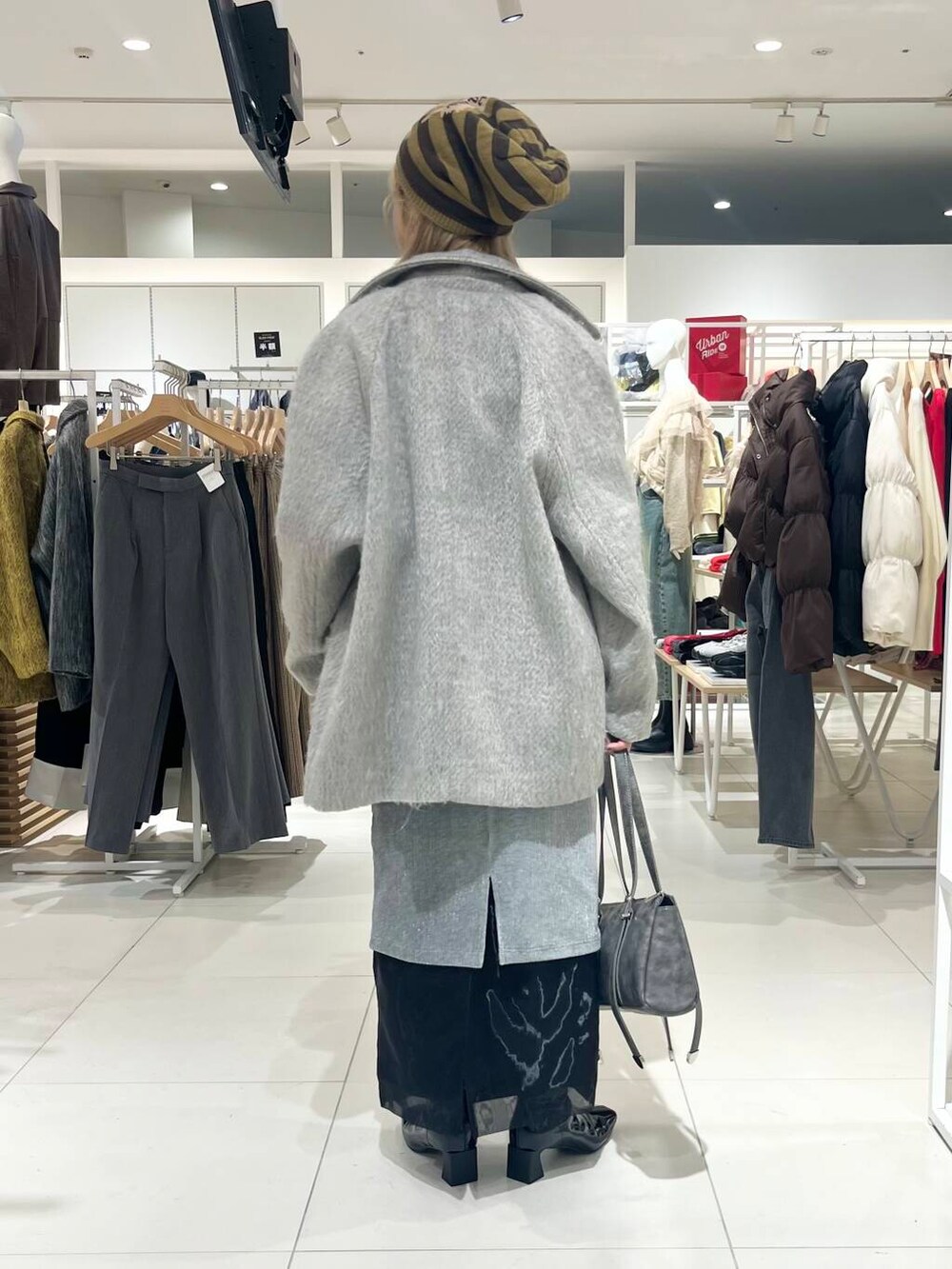 ブラック系のブーツ、ブラック系のスカート、グレー系のボストンバッグを着用したレディースの秋コーディネートの4枚目の写真