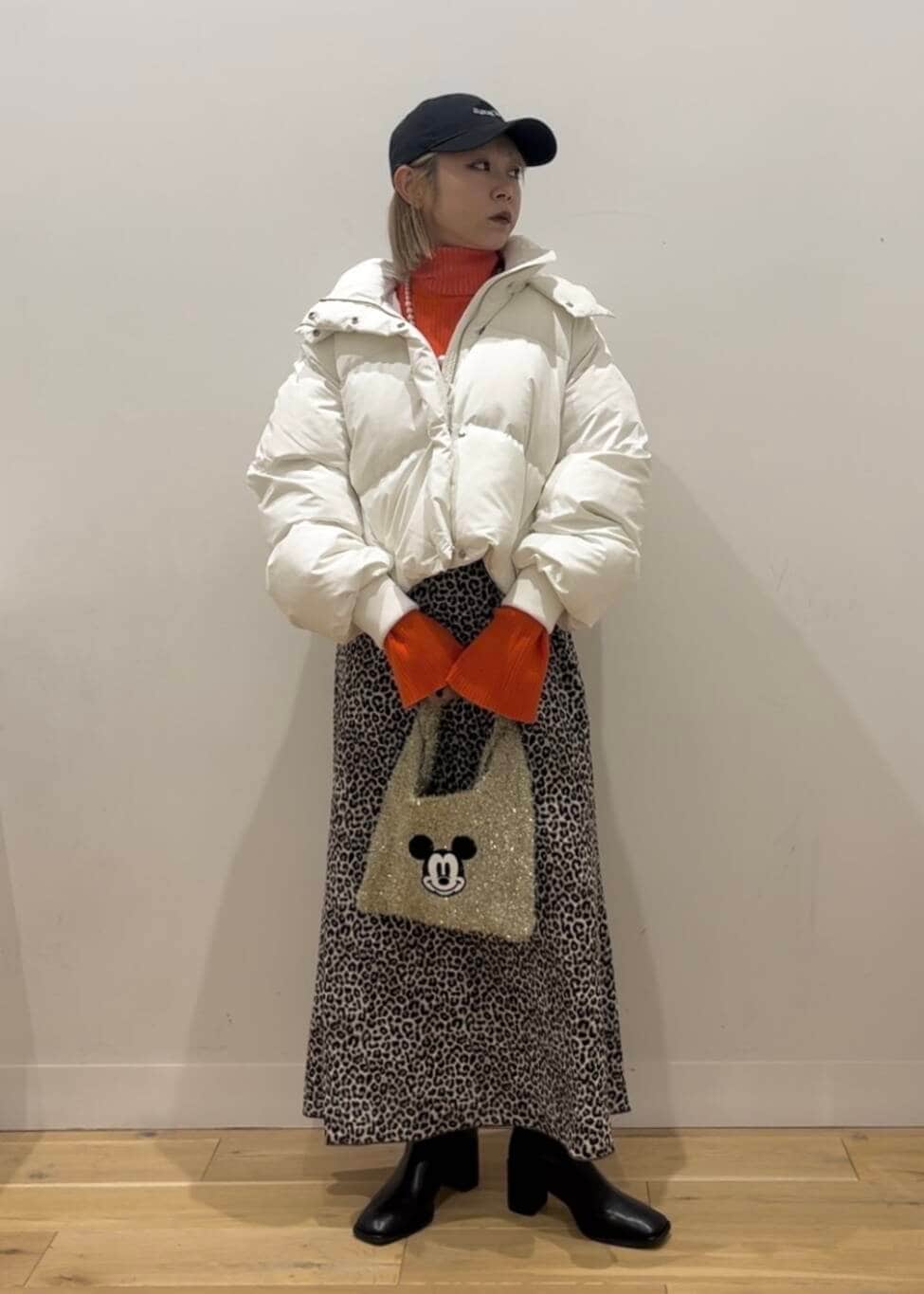 ホワイト系のダウンジャケット/コート、ブラック系のブーツ、ゴールド系のトートバッグを着用したレディースの秋コーディネートの2枚目の写真