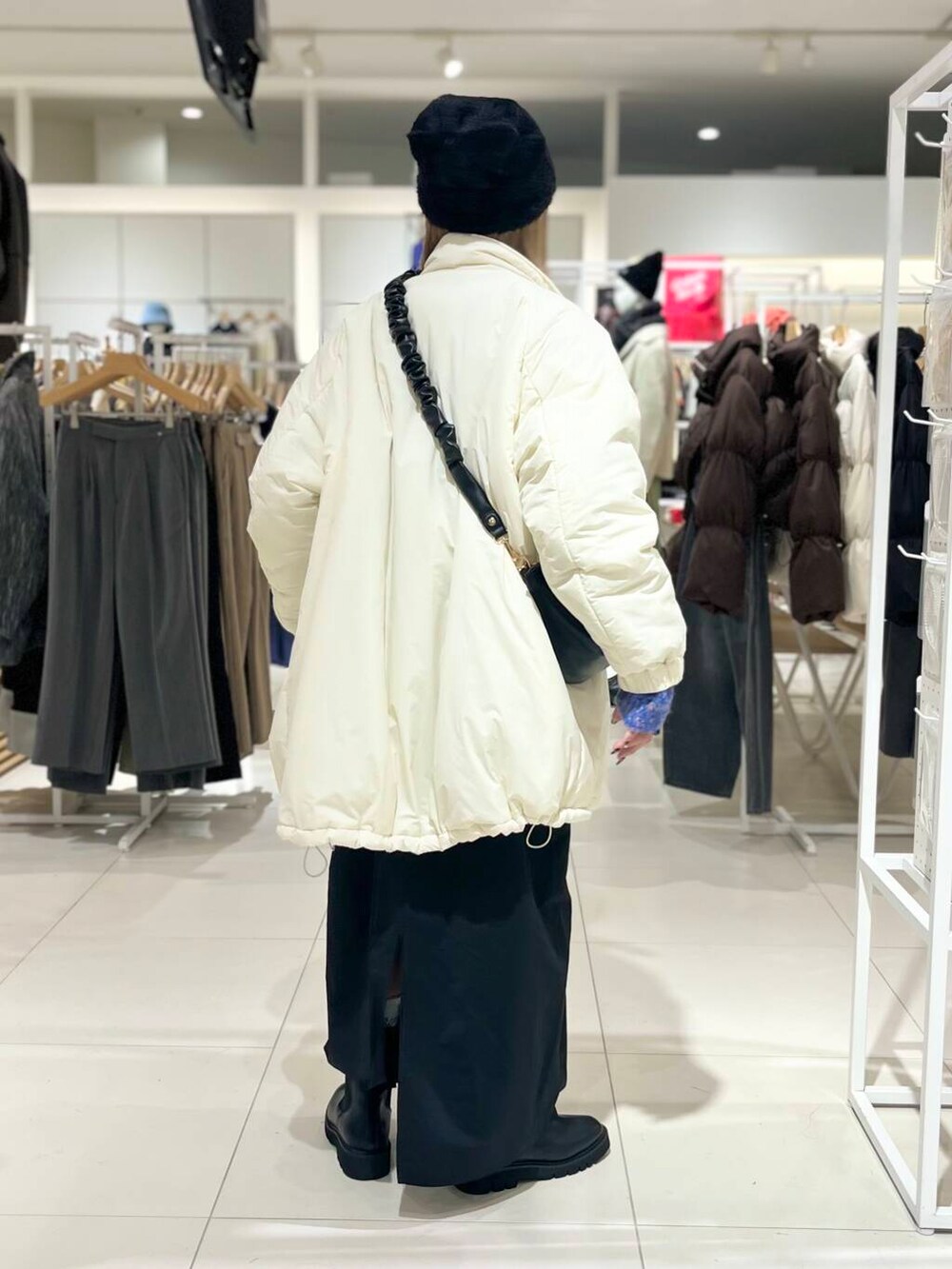 ブラック系のブーツ、ブラック系のショルダーバッグ、ブラック系のワンピースを着用したレディースの冬コーディネートの3枚目の写真