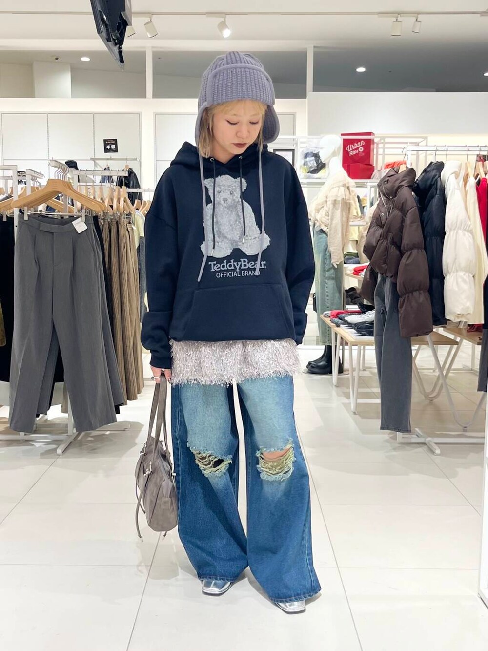 シルバー系のブーツ、ブルー系のデニムパンツ、ブラウン系のボストンバッグを着用したレディースの冬コーディネートの2枚目の写真