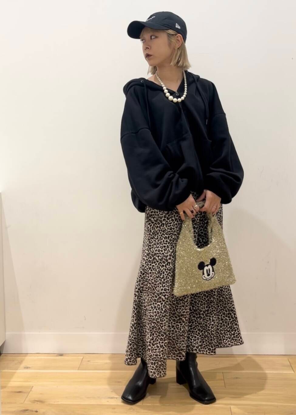 ブラック系のブーツ、ゴールド系のトートバッグ、ブラウン系のスカートを着用したレディースの秋コーディネートの2枚目の写真